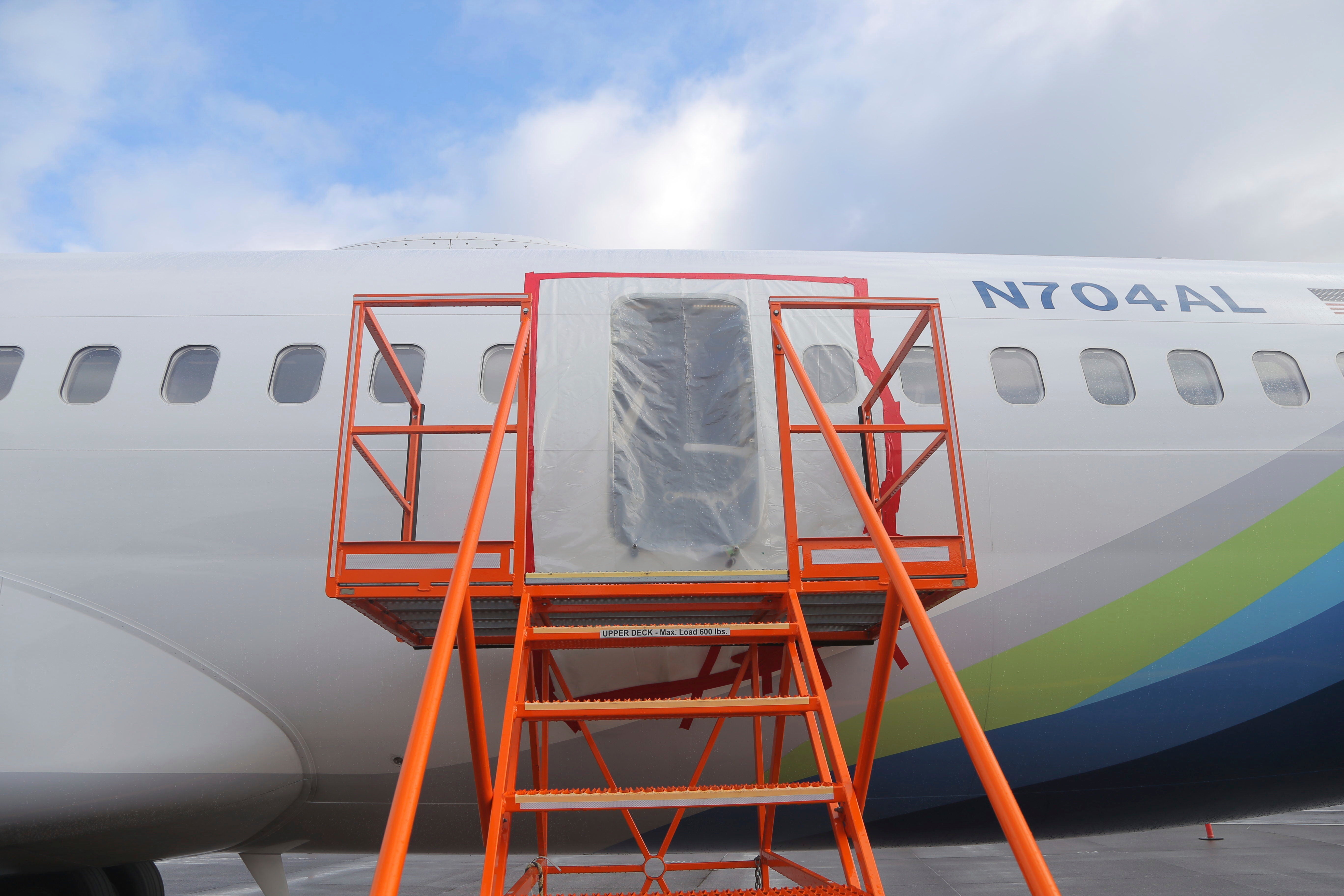 A photo released by the National Transportation Safety Board shows a gaping hole where the paneled-over door had been at the fuselage plug area of Alaska Airlines Flight 1282