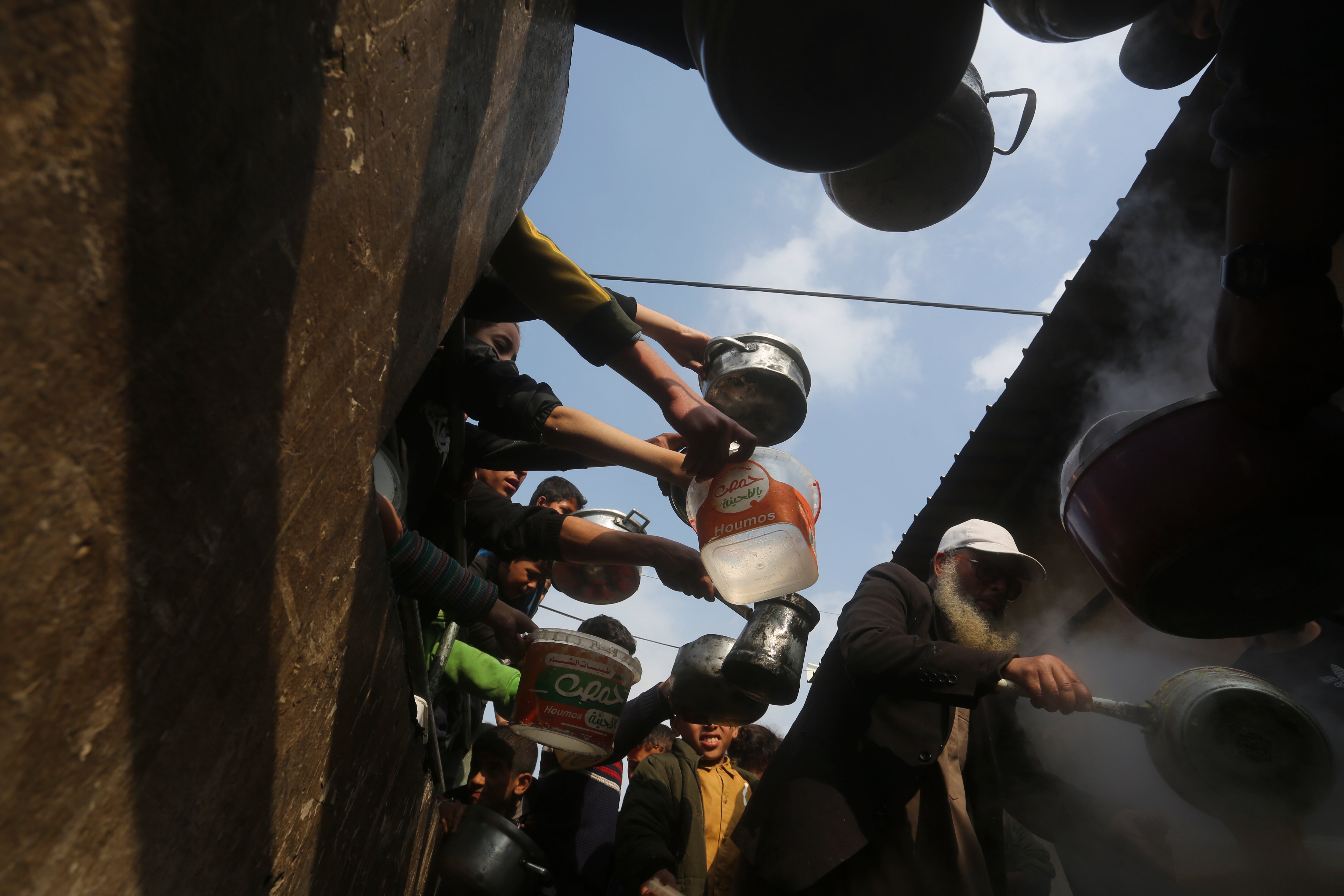 Palestinians line up for free food during the ongoing Israeli air and ground offensive on the Gaza Strip in Rafah, Tuesday, Jan. 9, 2024.