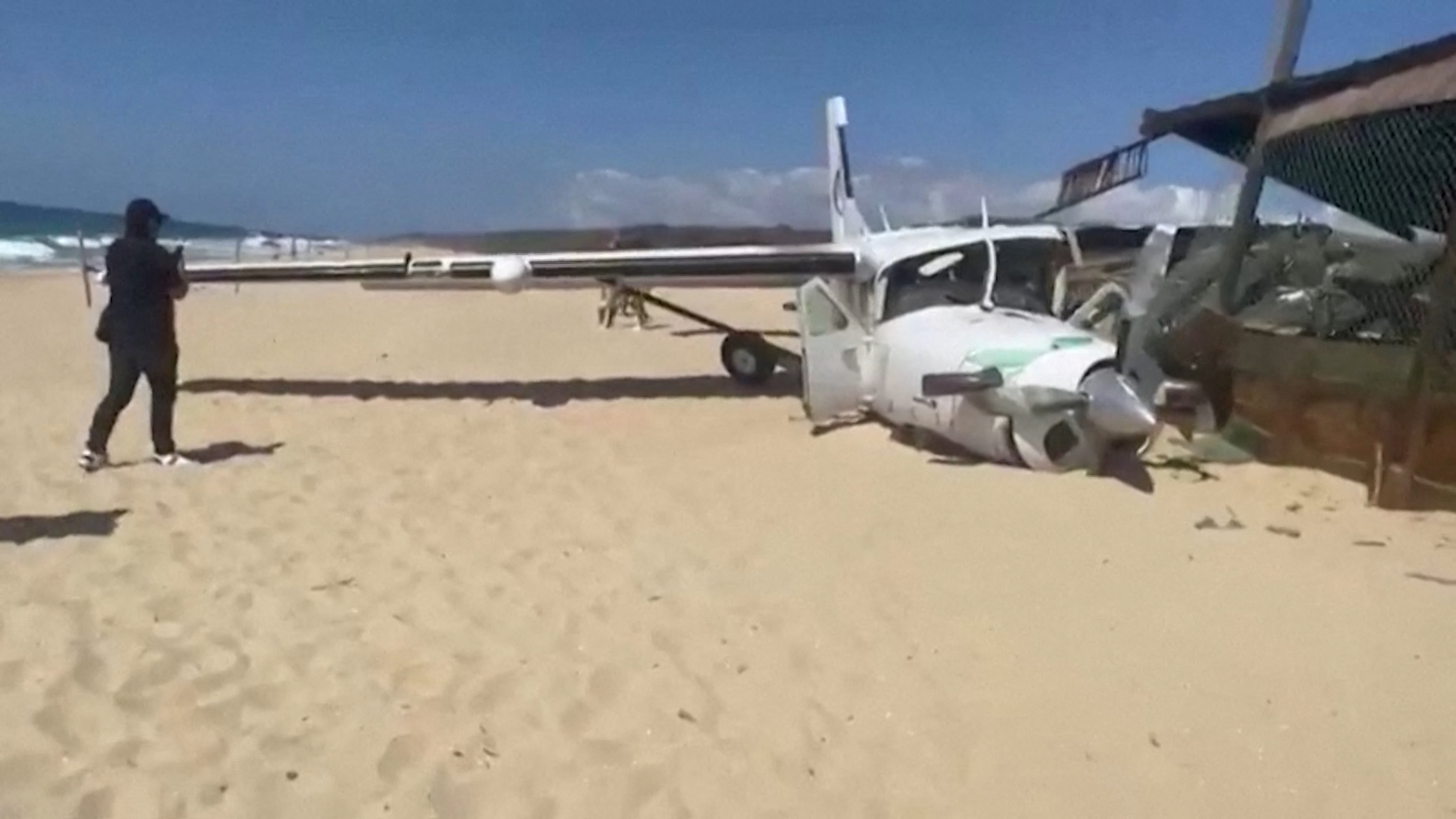 A person stands near the wreckage of a small plane that crashed into a sea turtle preservation site at Bacocho beach, in Oaxaca state