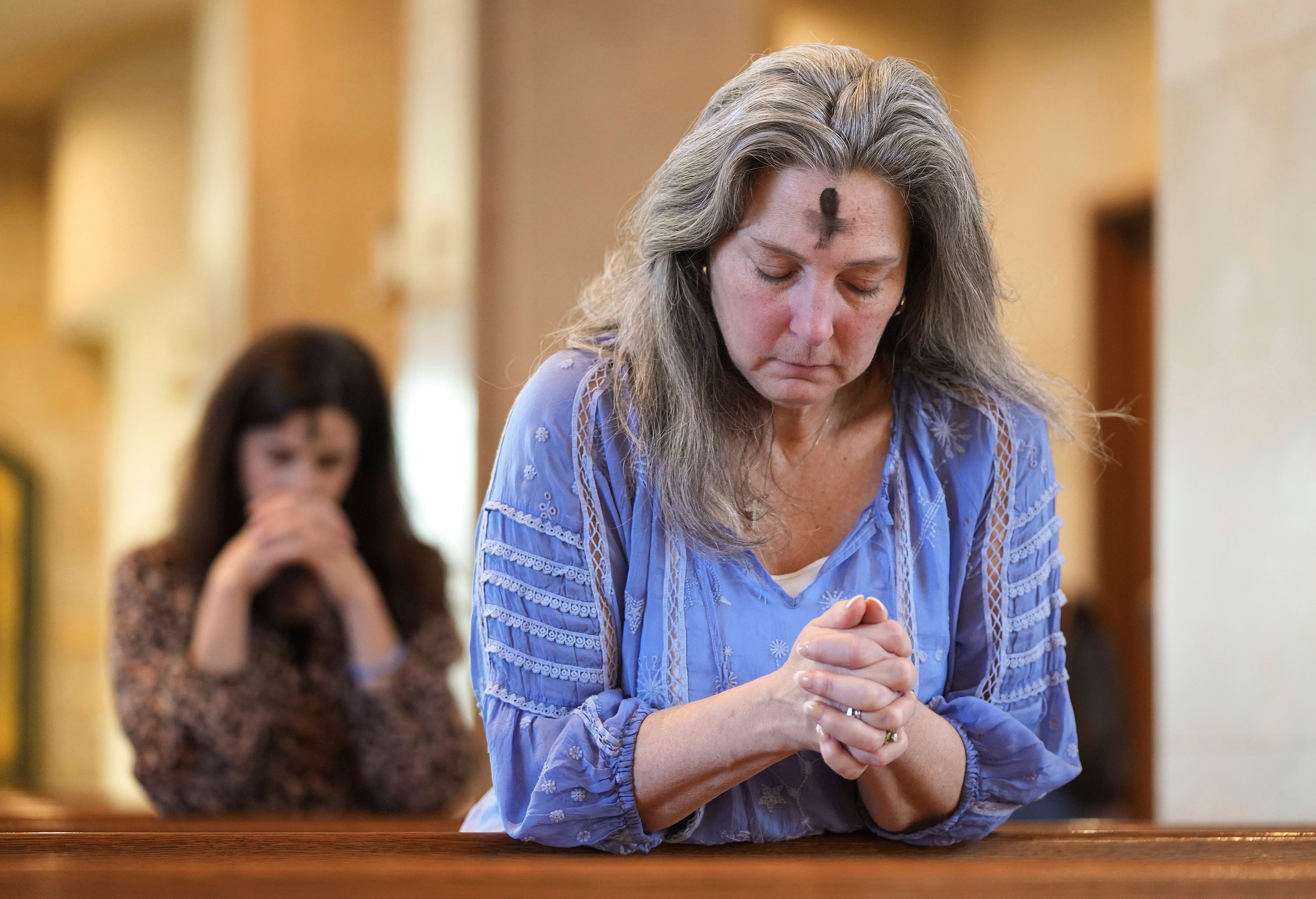 FILE - Dorsey Prince, right, and Shannon Carter pray during an Ash Wednesday Mass at St. John Neumann Catholic Church