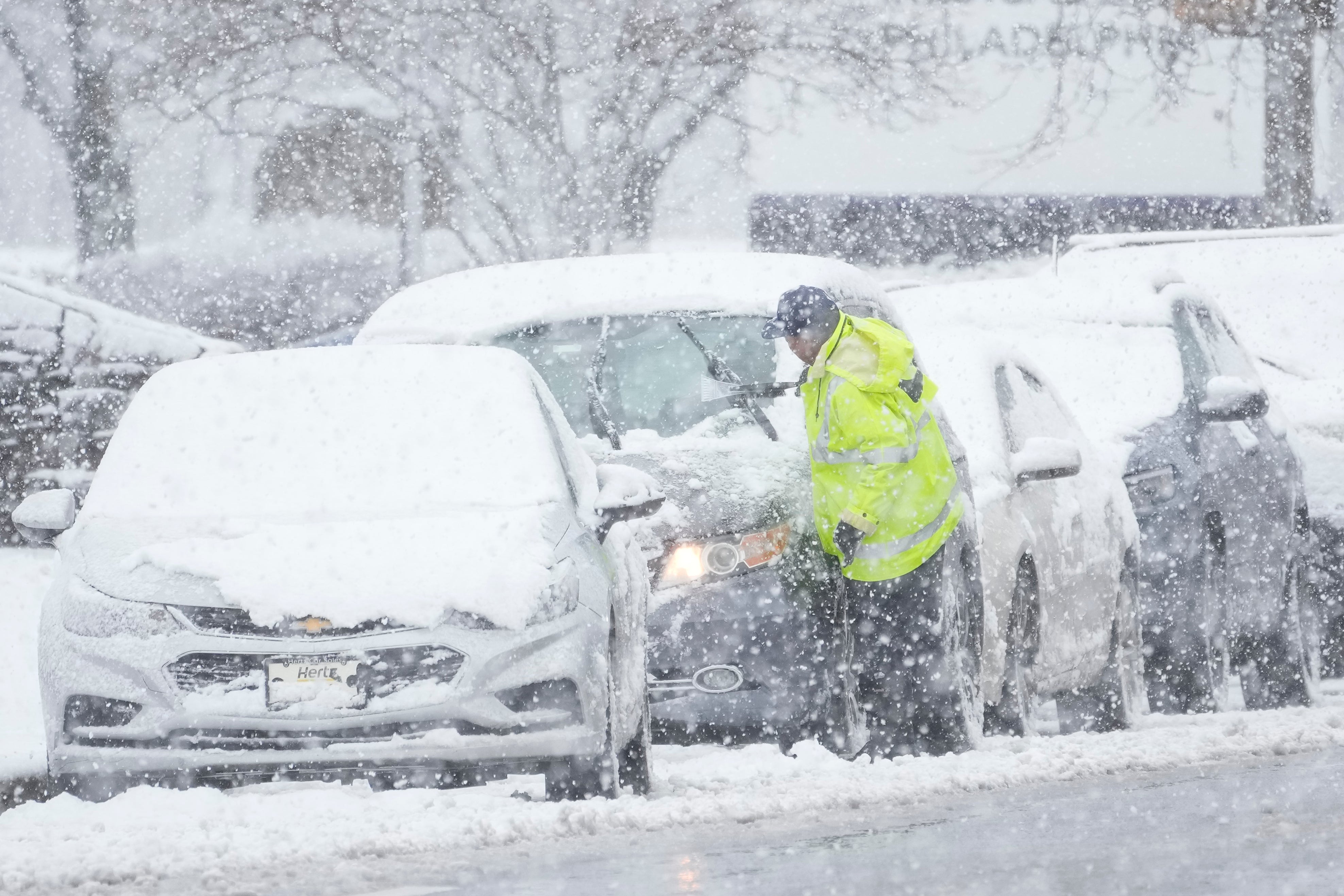 A driver cleans snow off a car in Philadelphia