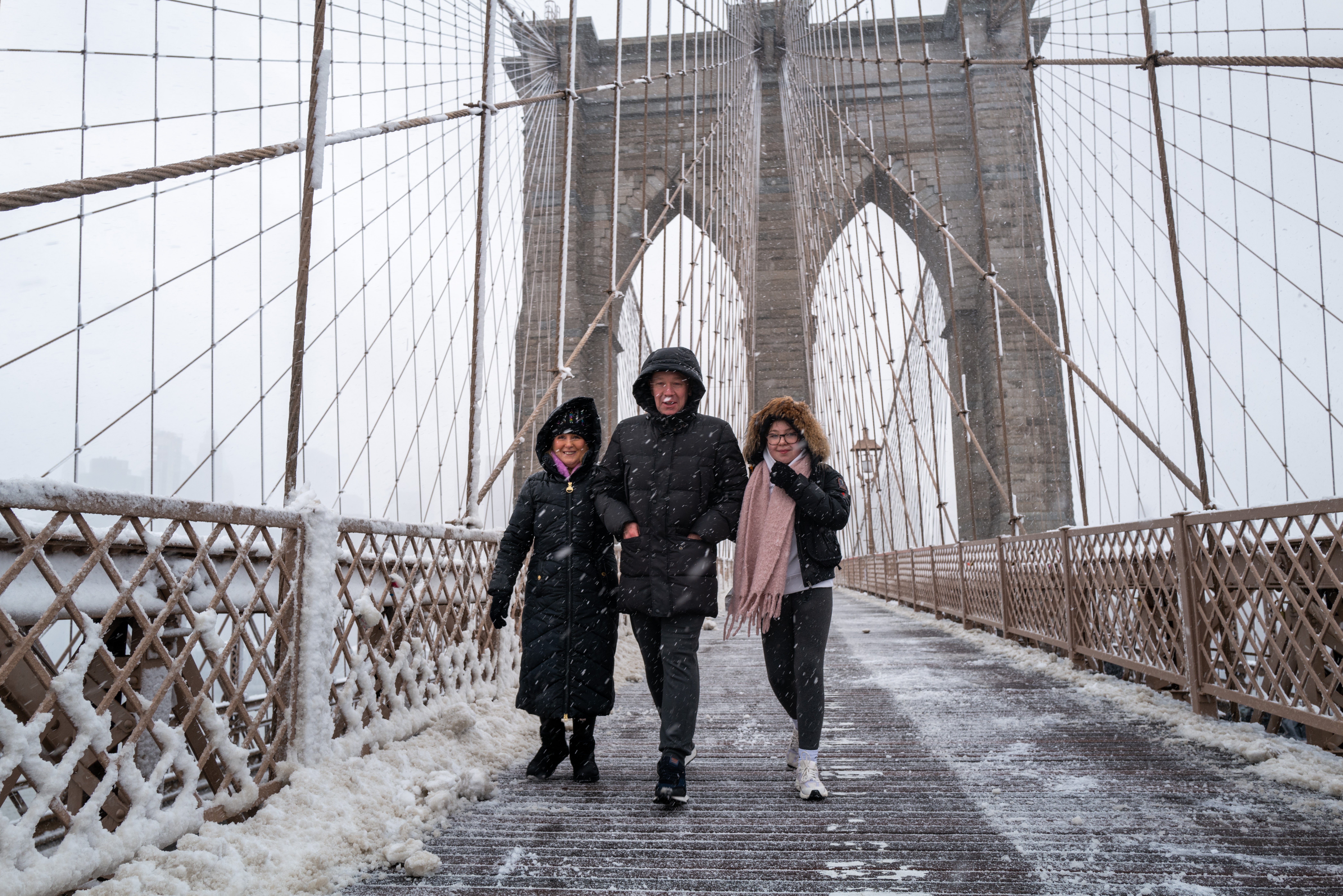 People walk across the Brooklyn Bridge in the blowing snow in Manhattan as a large winter storm makes its way across the area