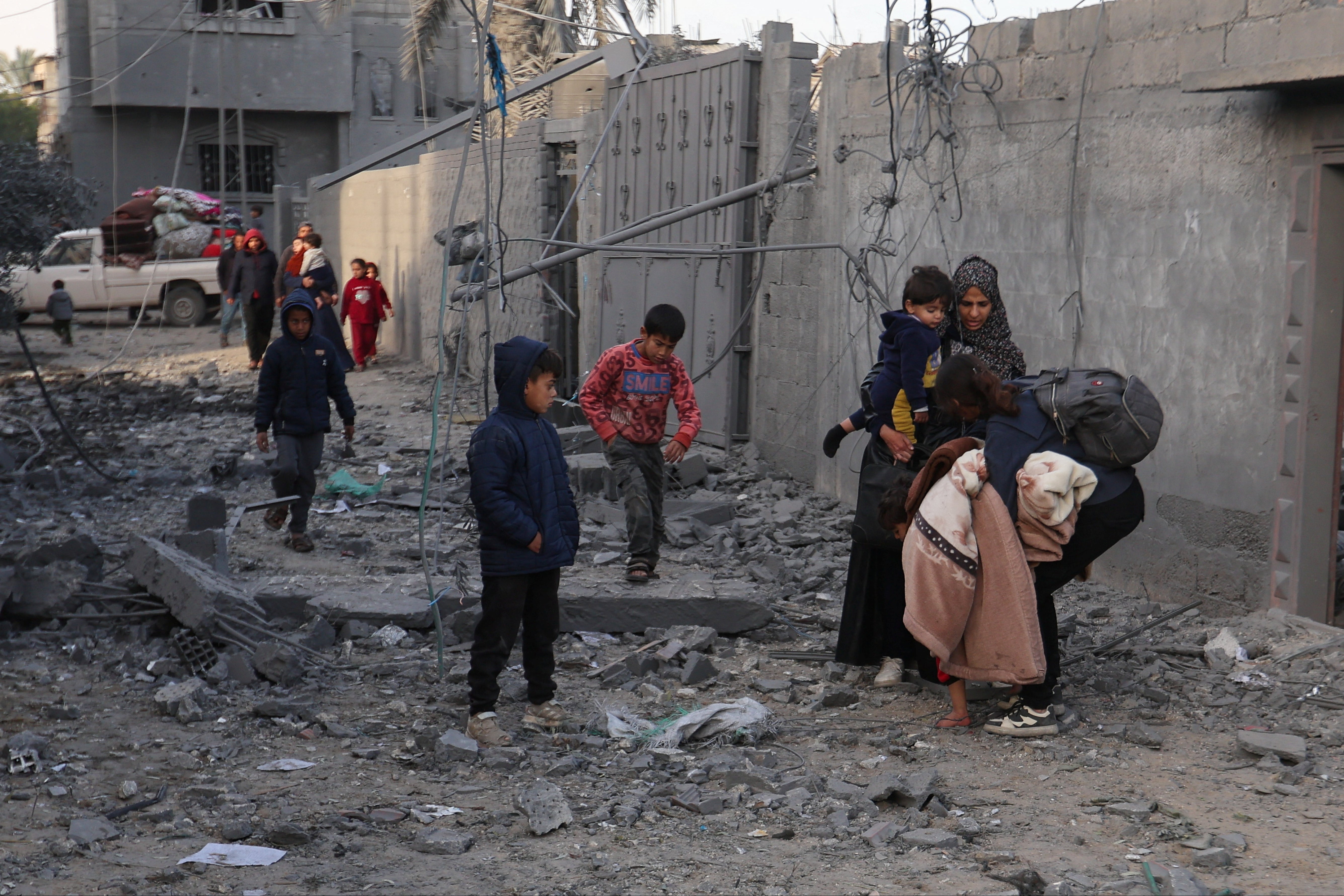 Palestinians walk at the site of an Israeli strike on a house, in Rafah