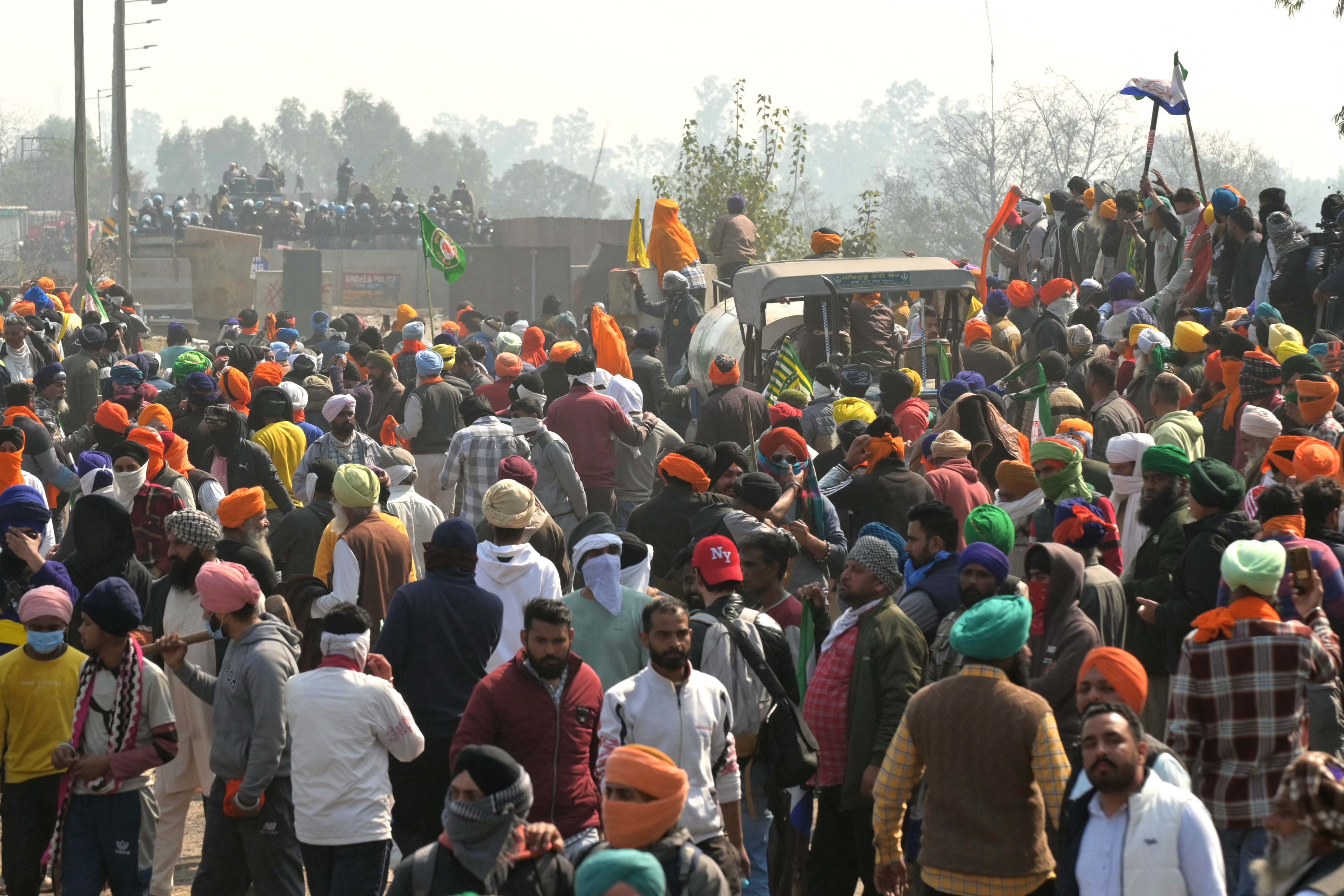 Police and Rapid Action Force (RAF) personnel (behind) block a highway to prevent farmers (front) from marching towards New Delhi