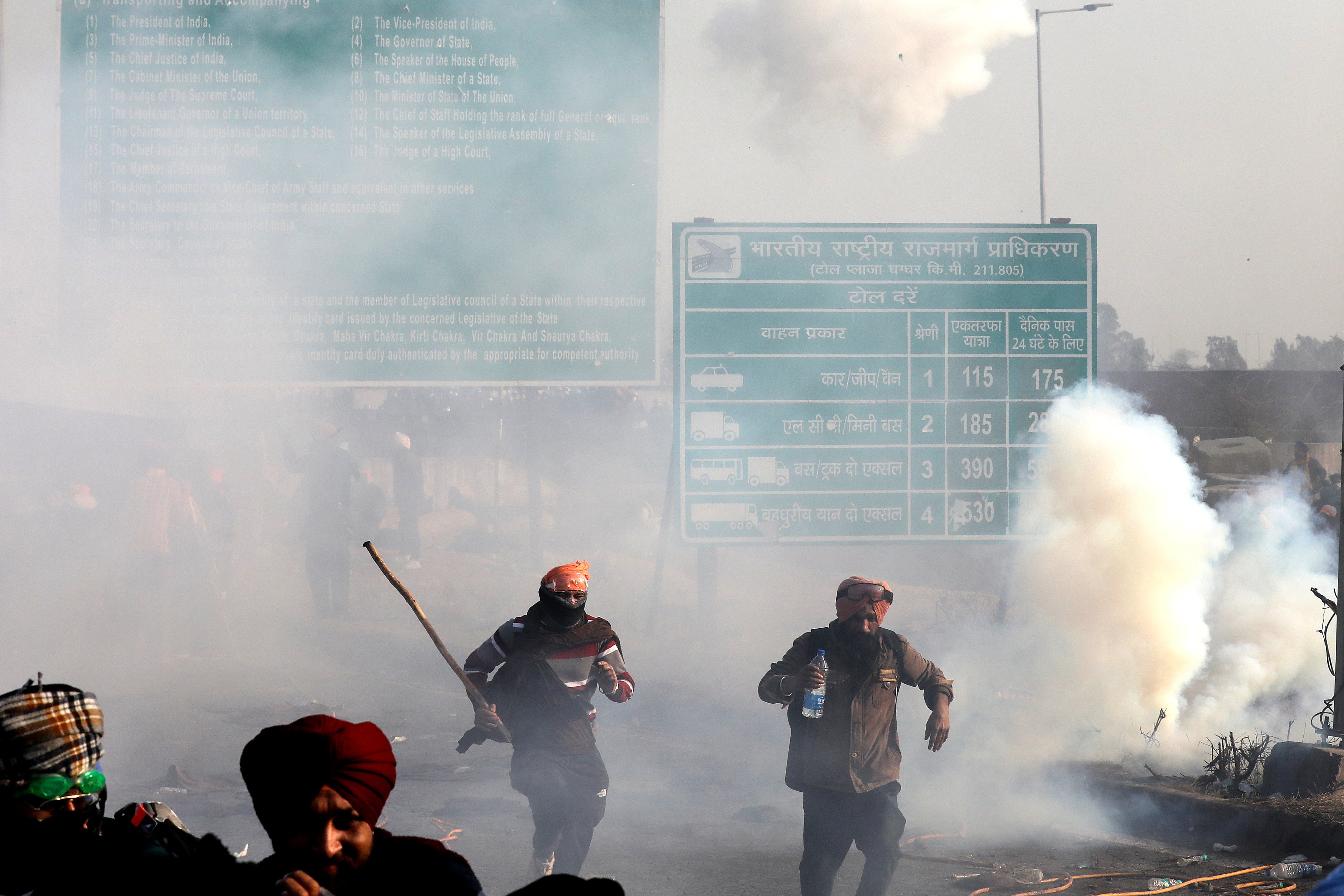 Protesting farmers run for cover as Indian Police fires teargas to prevent them from moving towards Delhi on the second day of their protest at Shambhu Haryana-Punjab border point