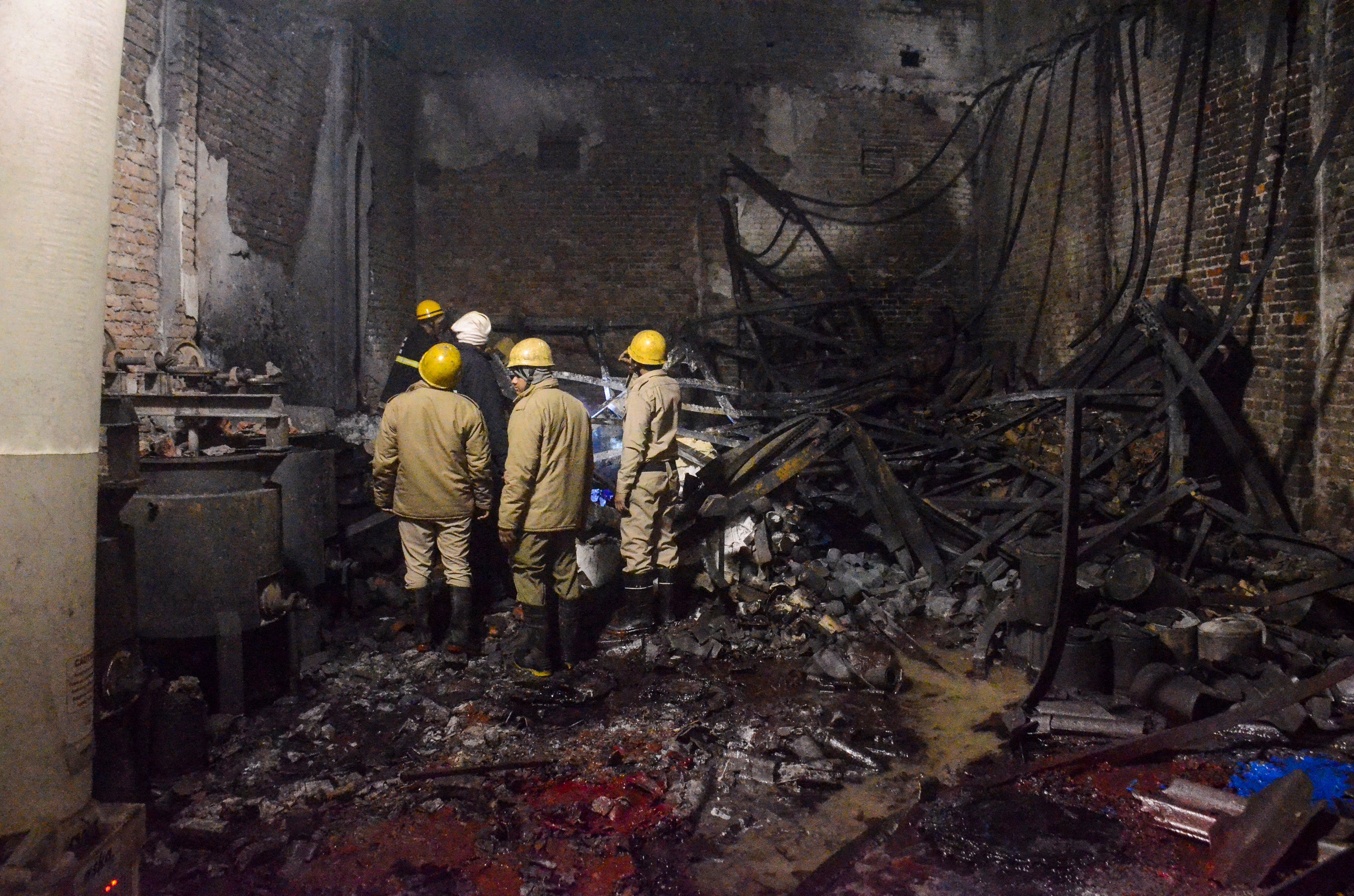 Fire brigade personnel look on after dousing a late Thursday fire at a paint factory in the Alipur area in northern New Delhi, India, Friday, 16 February 2024