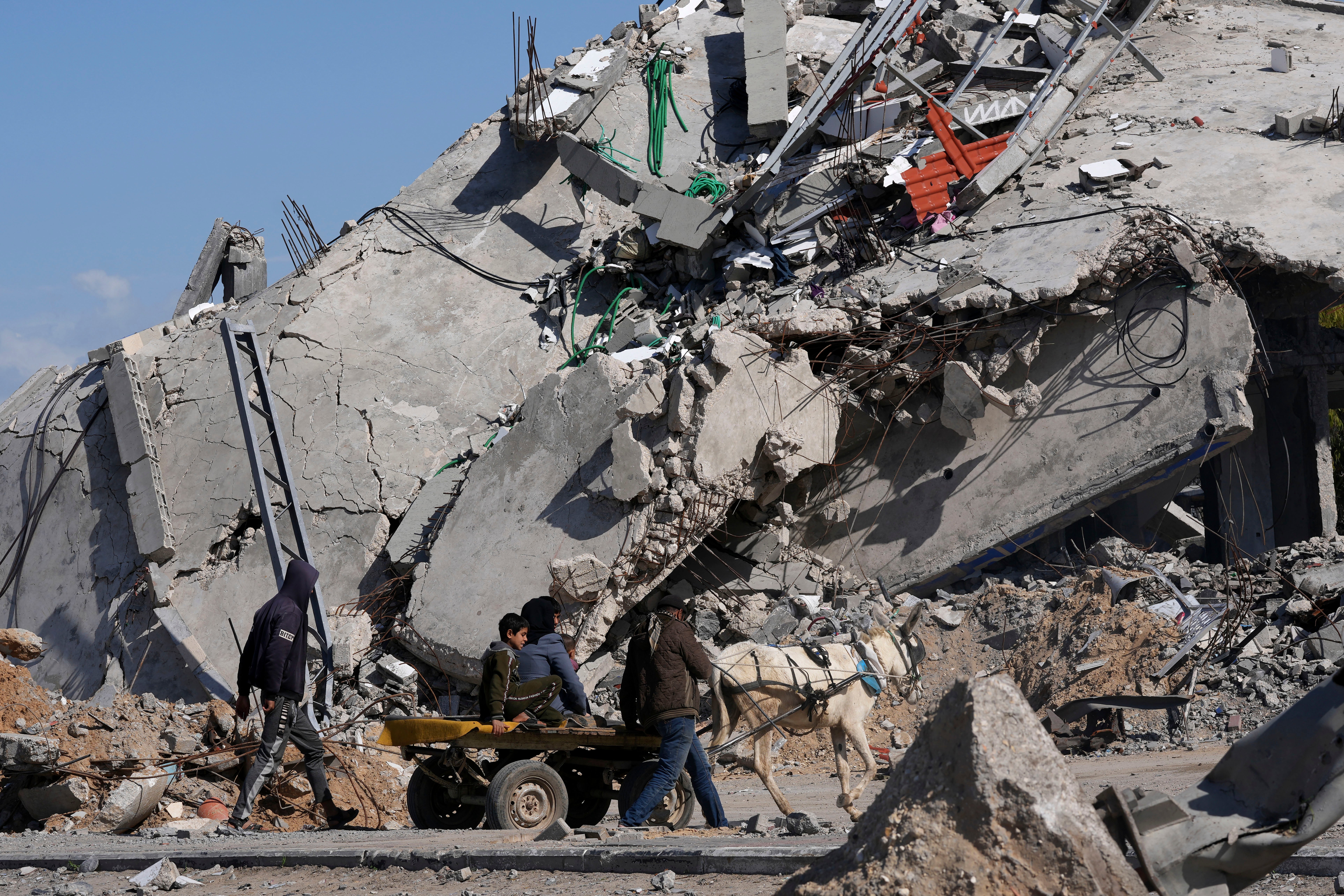 Palestinians ride on a donkey cart past factories destroyed in the Israeli bombardment of the Gaza Strip