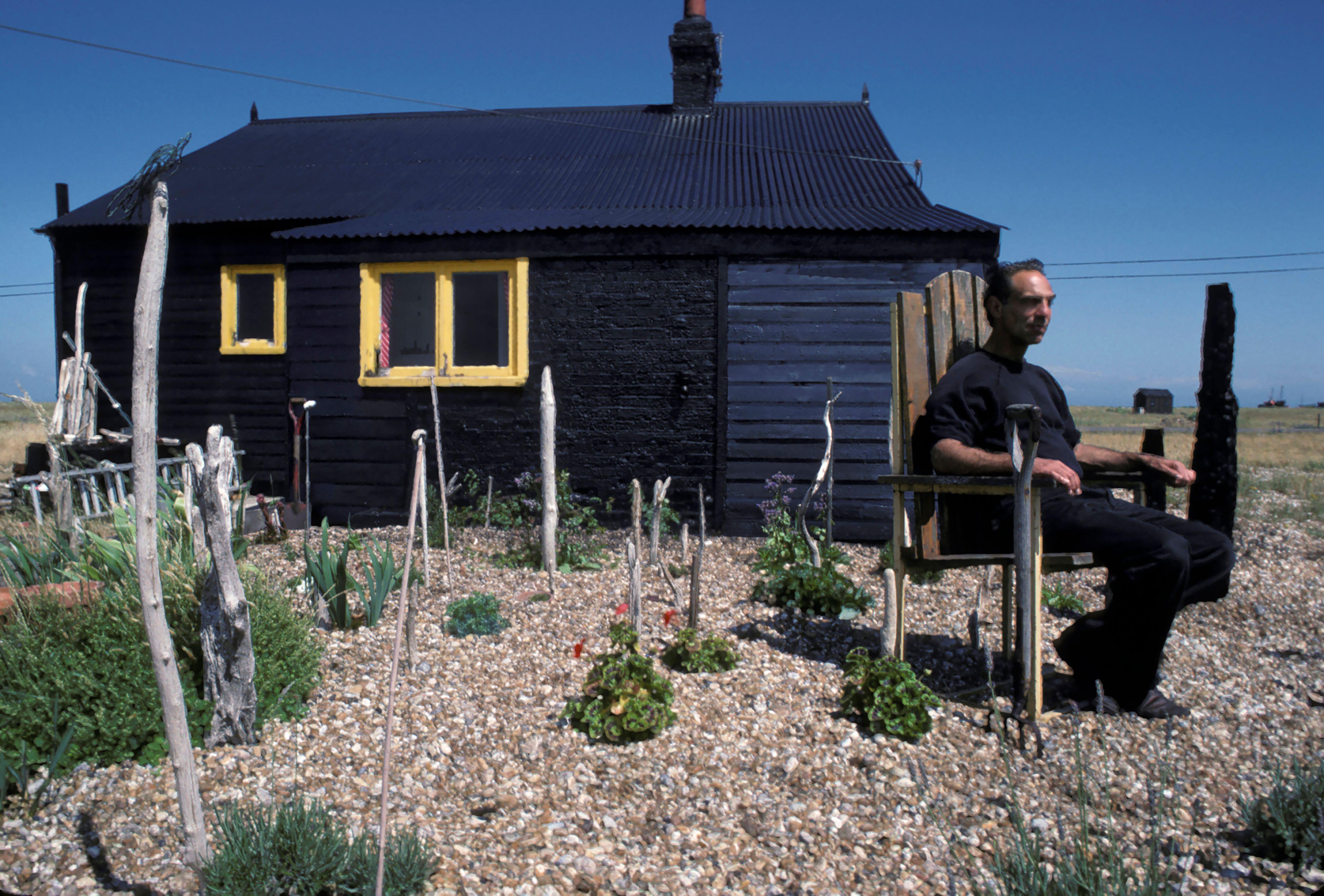 Derek Jarman in his shingle garden at Prospect Cottage, Dungeness