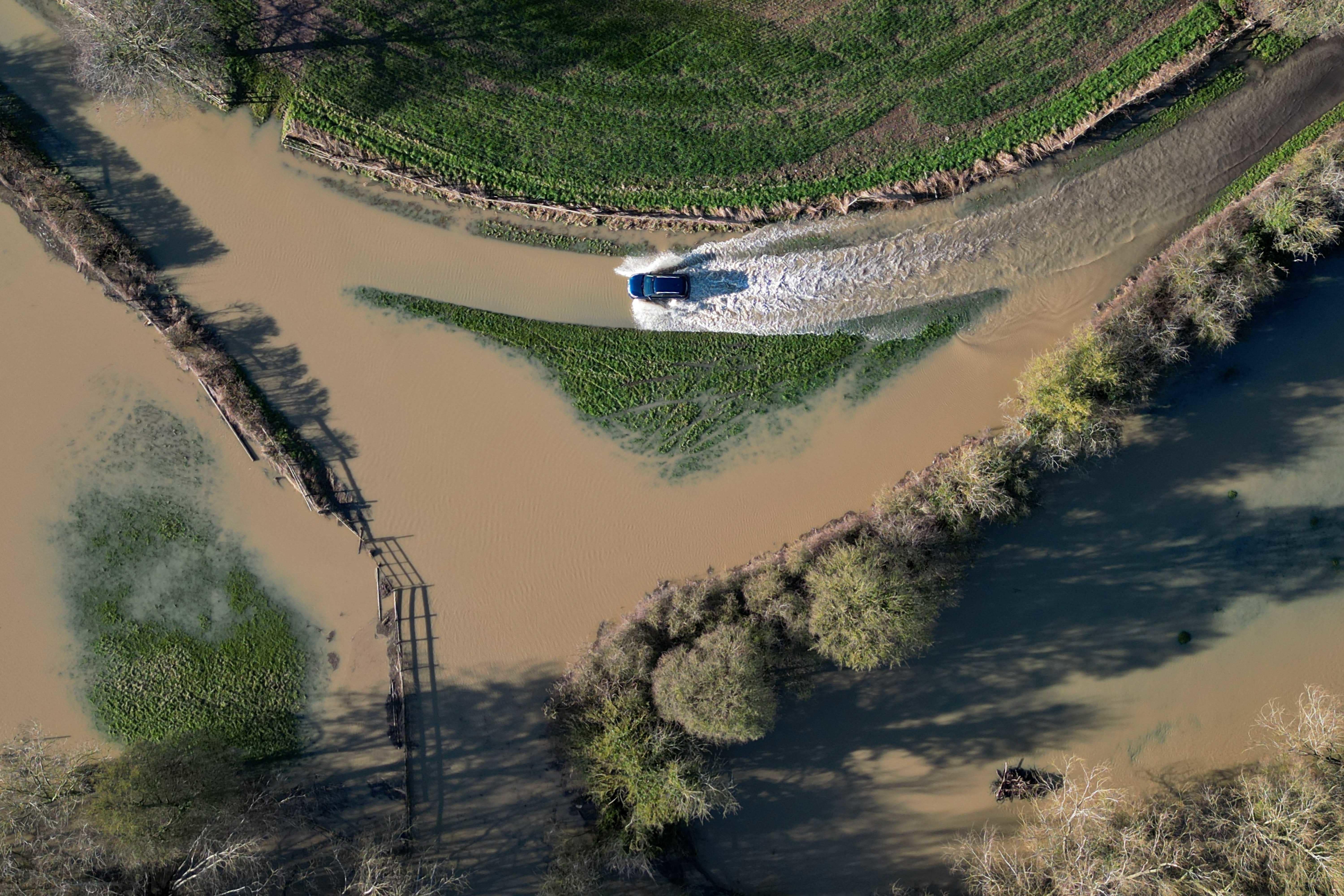 A vehicle passes through floodwater in Walton, near Stratford-upon-Avon, in Warwickshire (Jacob King/PA)