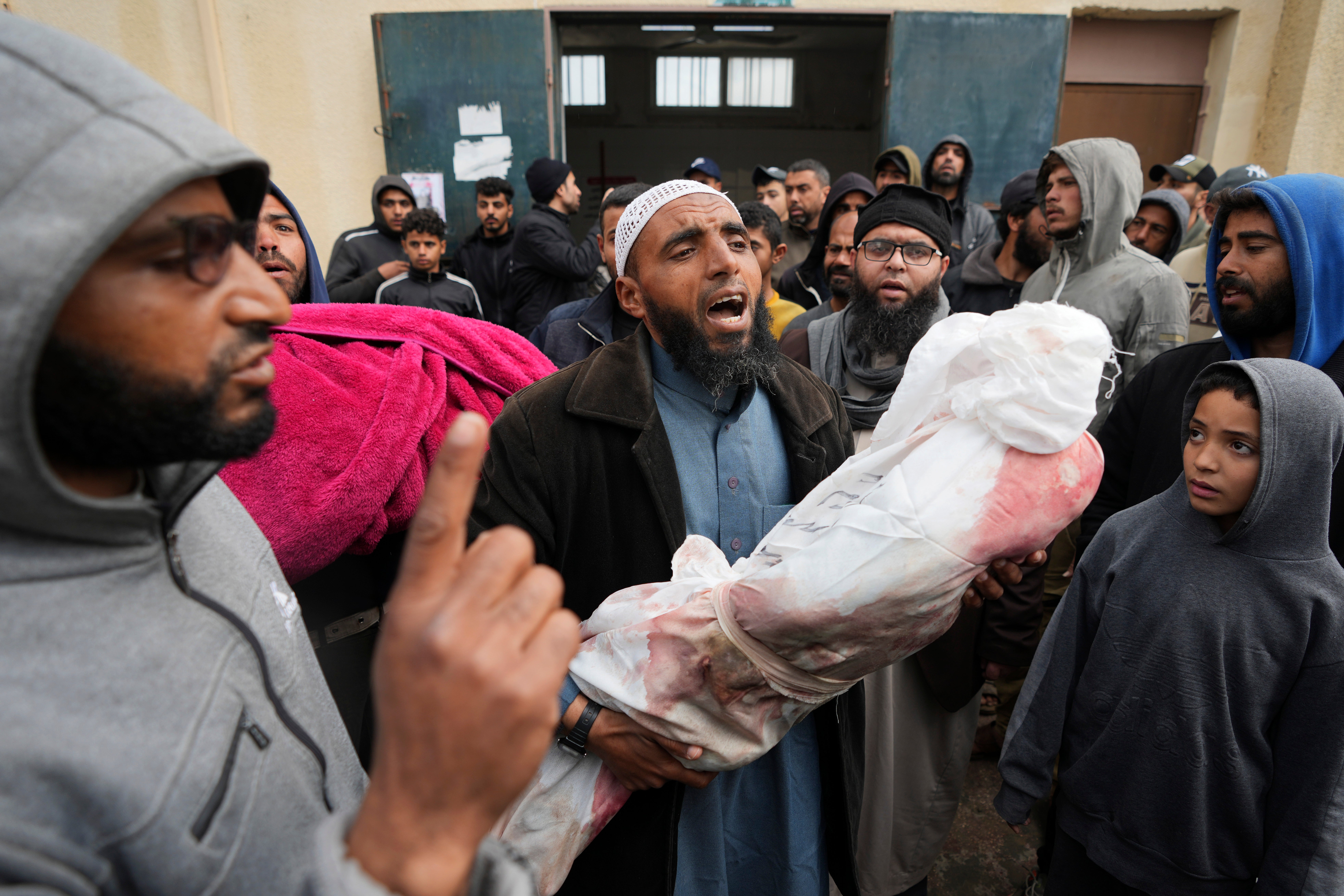 Palestinians chant Islamic slogans while carry the bodies of children killed in the Israeli strikes in the Gaza Strip in front of the morgue at Al Aqsa hospital