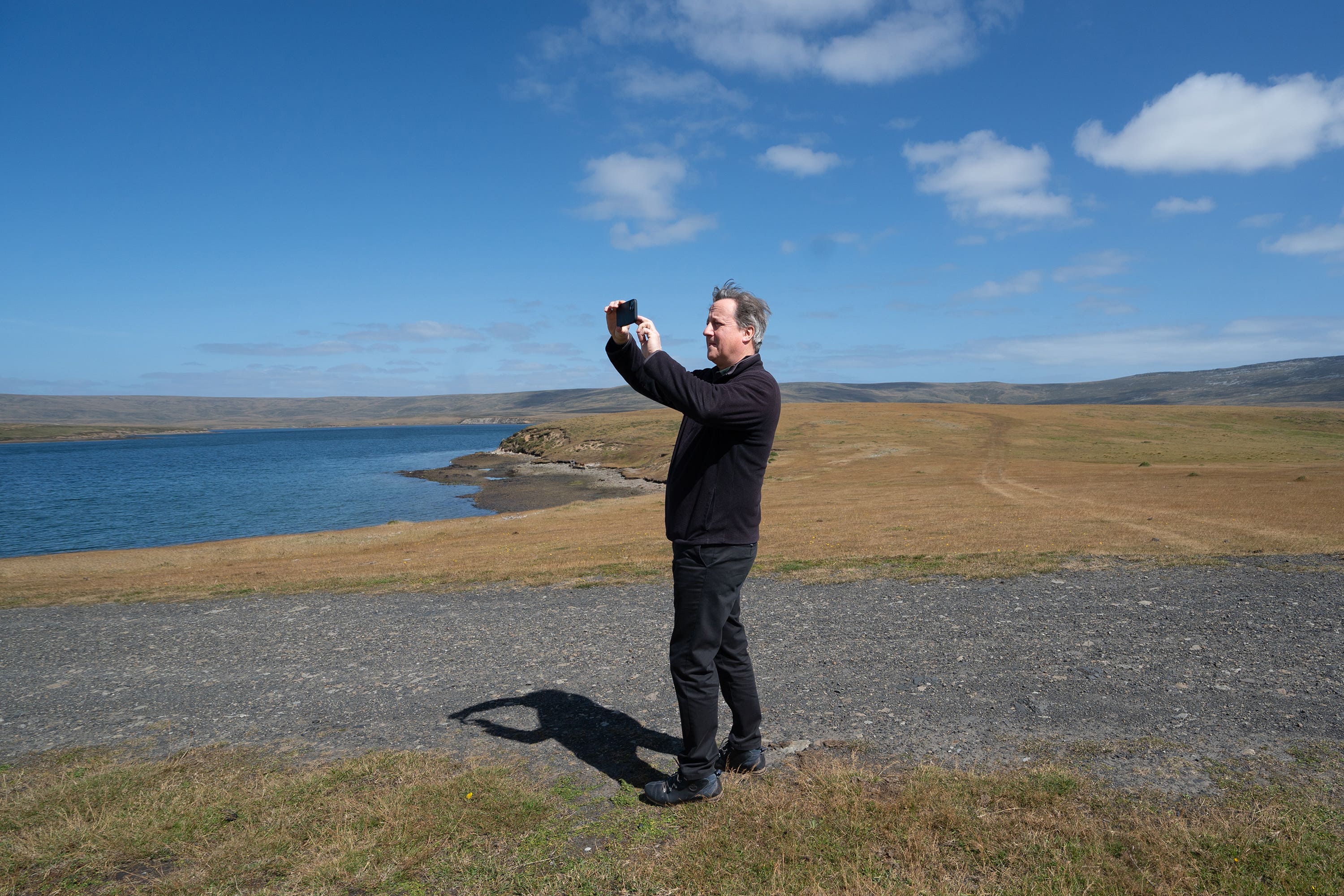 Foreign Secretary Lord David Cameron takes a photograph of San Carlos Water (Stefan Rousseau/PA)