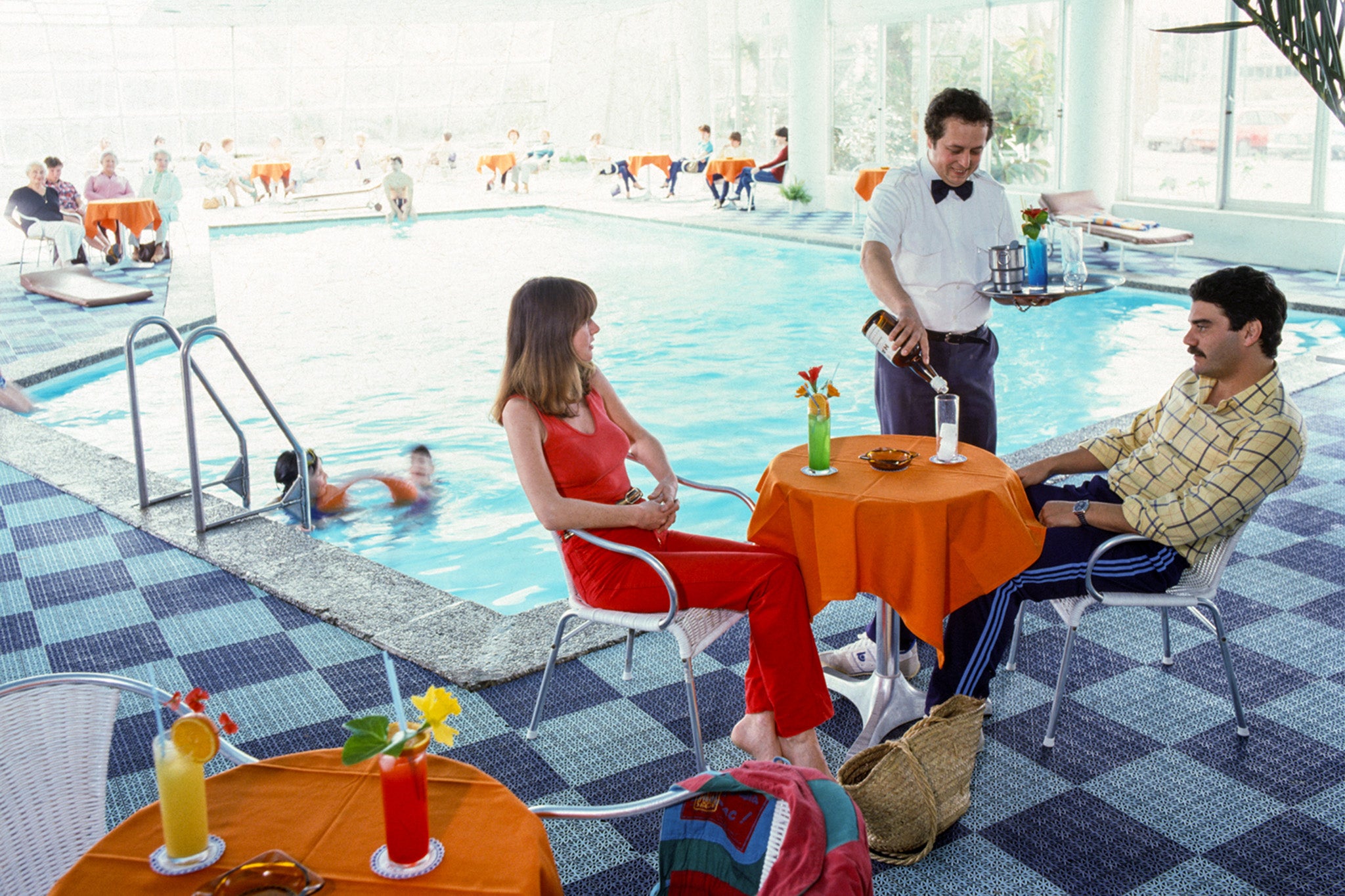 A couple lounging poolside with brightly coloured cocktails