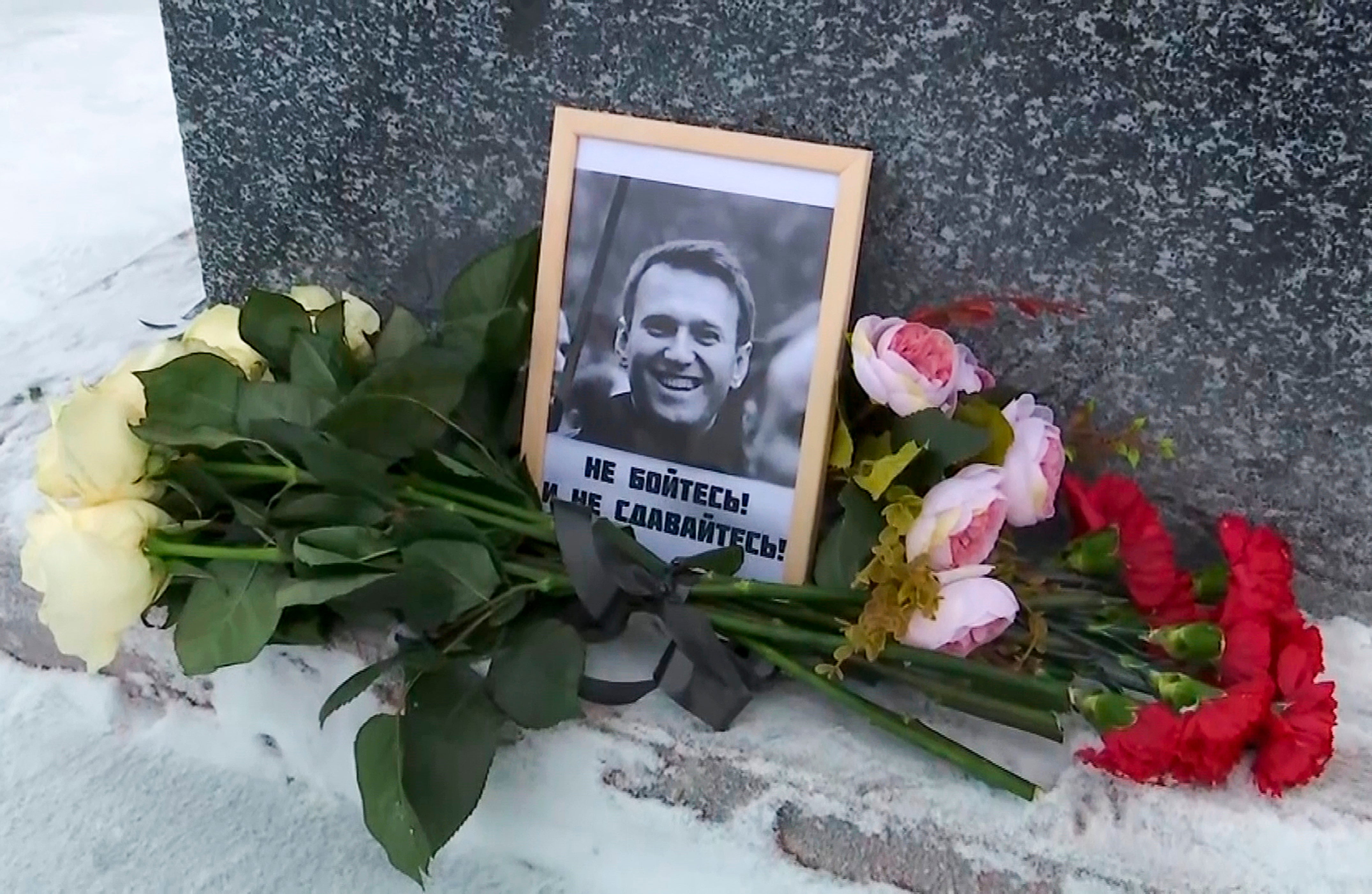 This grab taken from video shows flowers and a portrait of Russian opposition leader Alexei Navalny that Lyudmila Navalnaya, mother of Russian opposition leader Alexei Navalny, put to pay tribute to her son at the at the memorial to victims of political repression, in Salekhard, 1,937 km northeast of Moscow, Russia