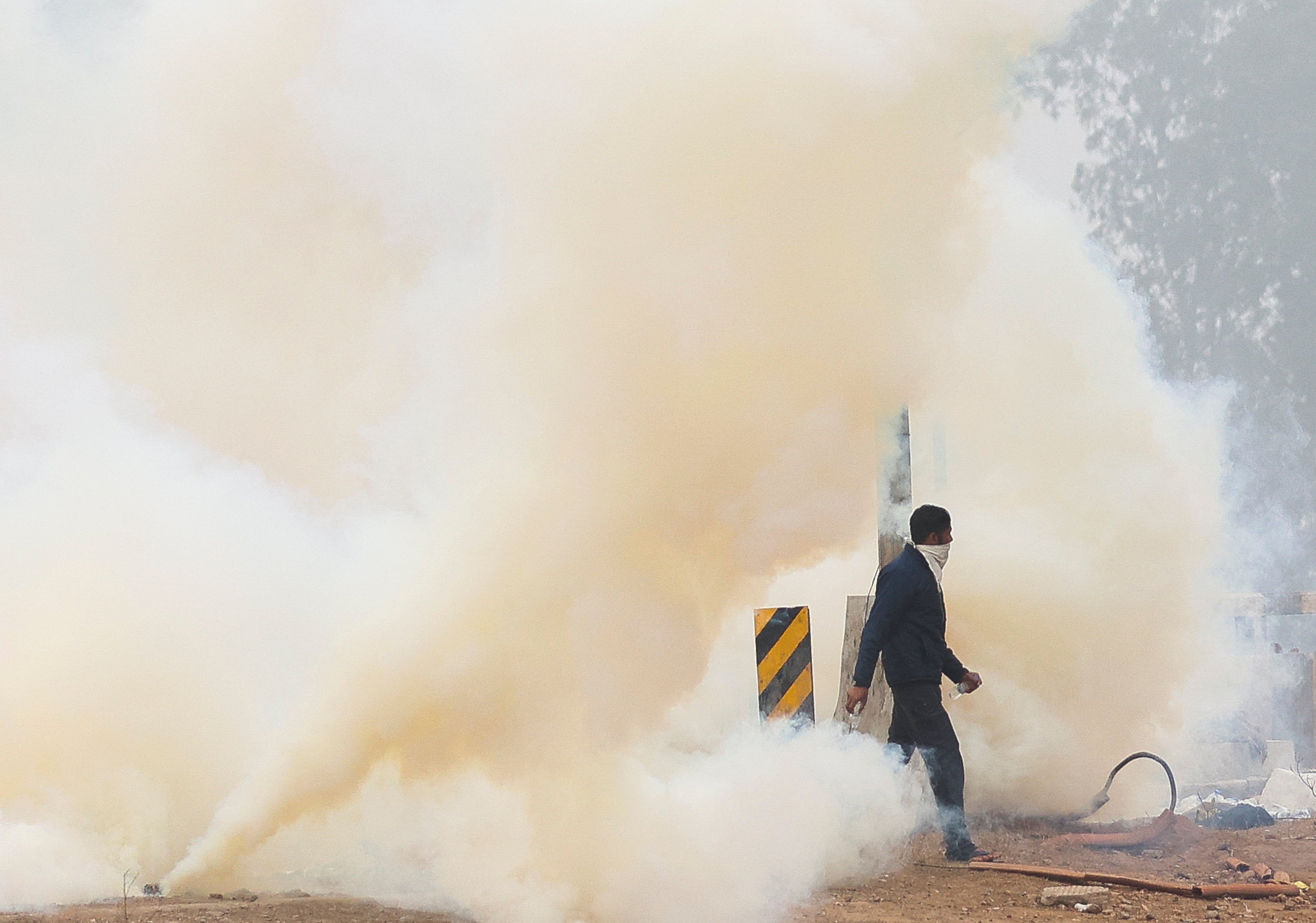 A man walks through tear gas at the site of the protest, as farmers march towards New Delhi to press for better crop prices promised to them in 2021, at Shambhu barrier, a border crossing between Punjab and Haryana states, India, 21 February 2024