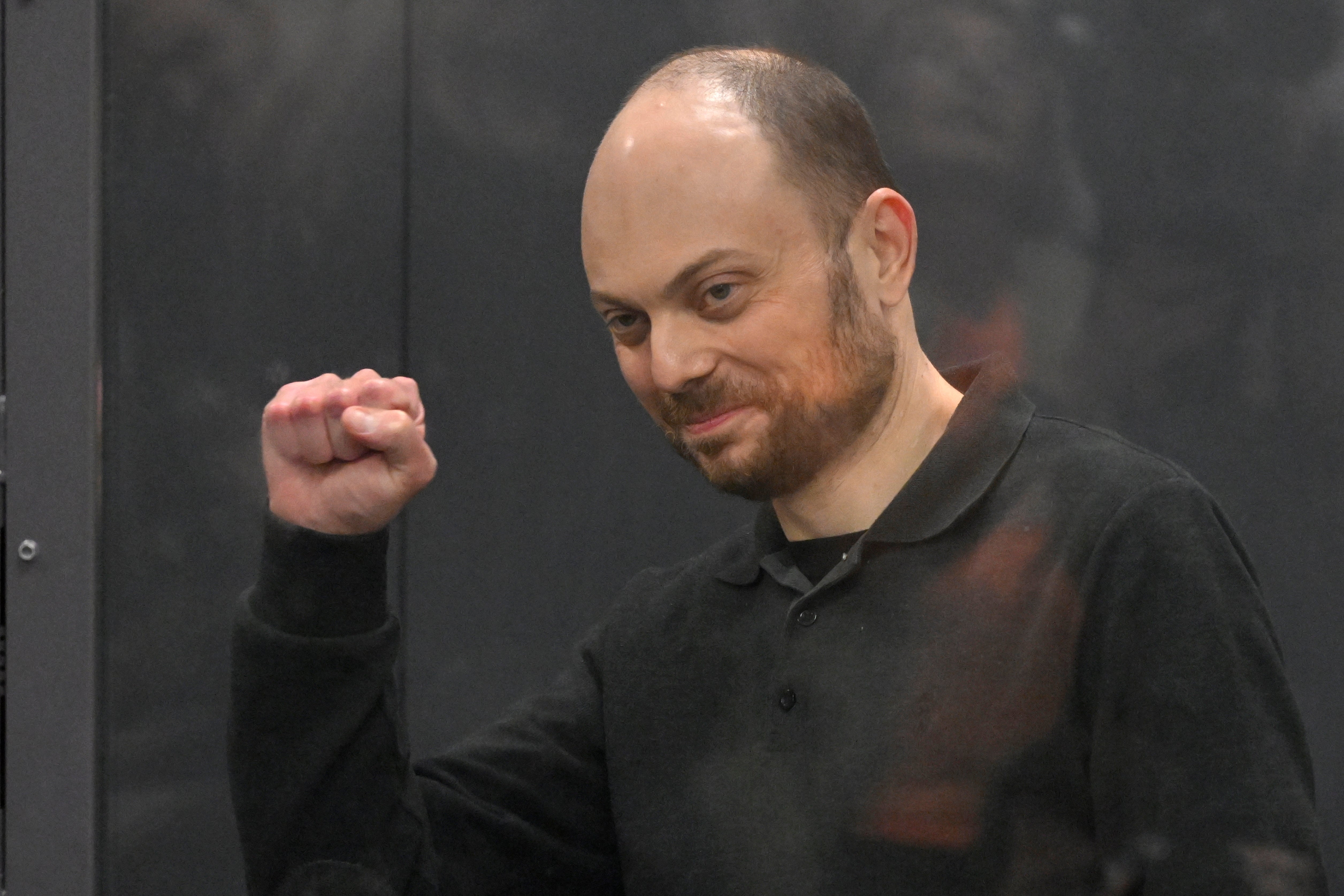 Vladimir Kara-Murza gestures from behind a glass cage in a Moscow courtroom last year