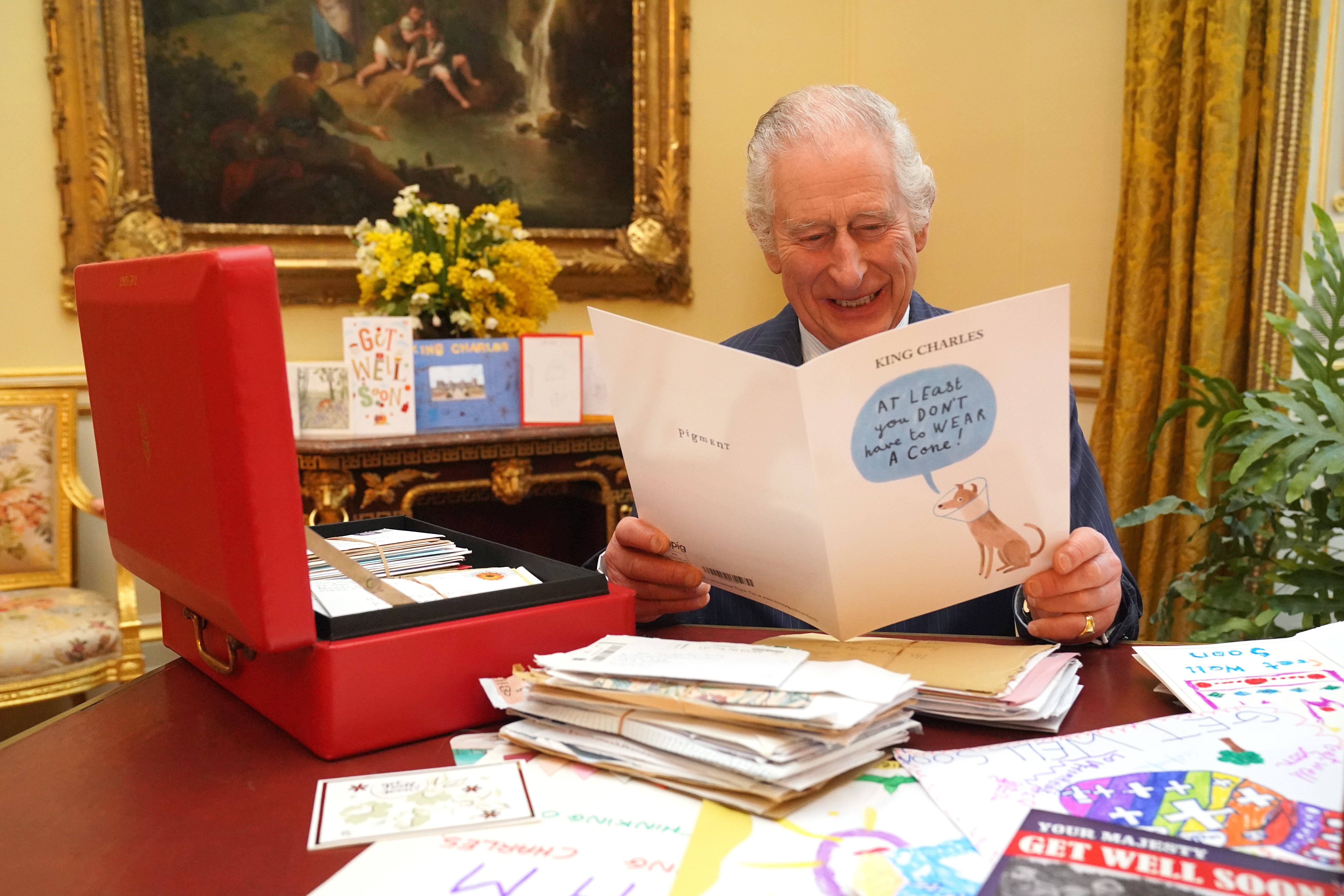 King Charles laughs as he opens cards from public