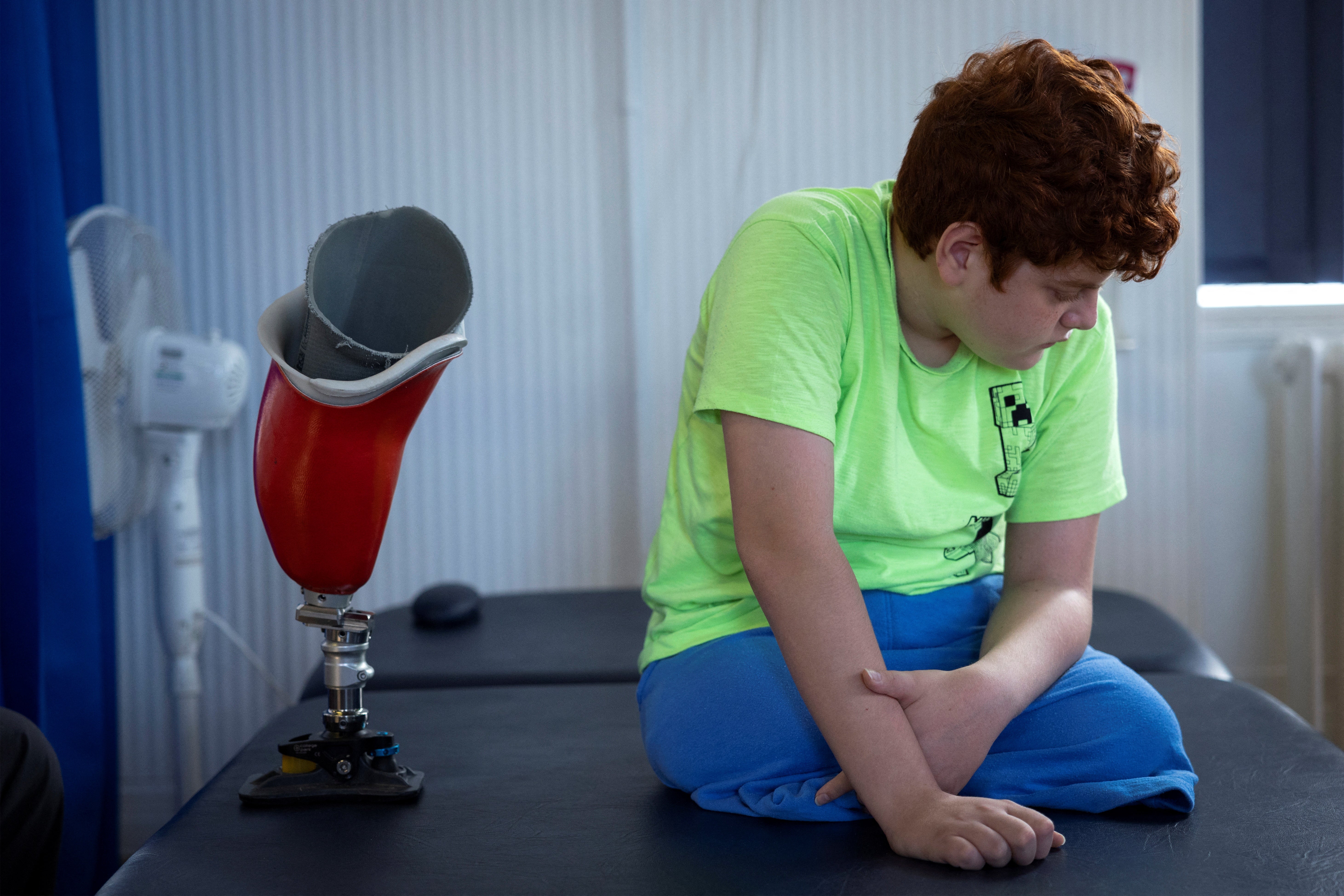 Mehmet, sits on a treatment bed as he is seen by specialists at the hospital