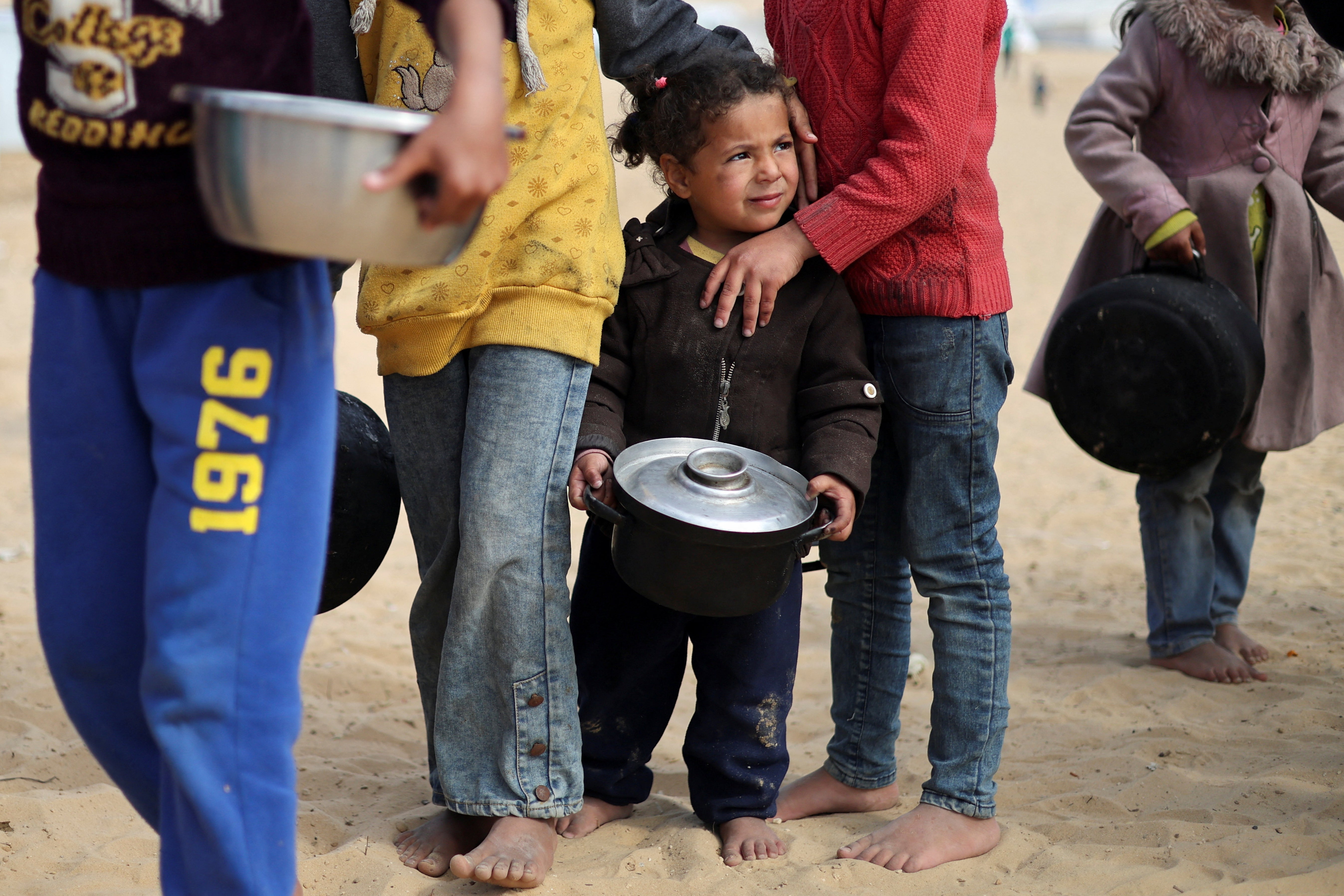 Displaced Palestinian children wait to receive food at a tent camp in Rafah