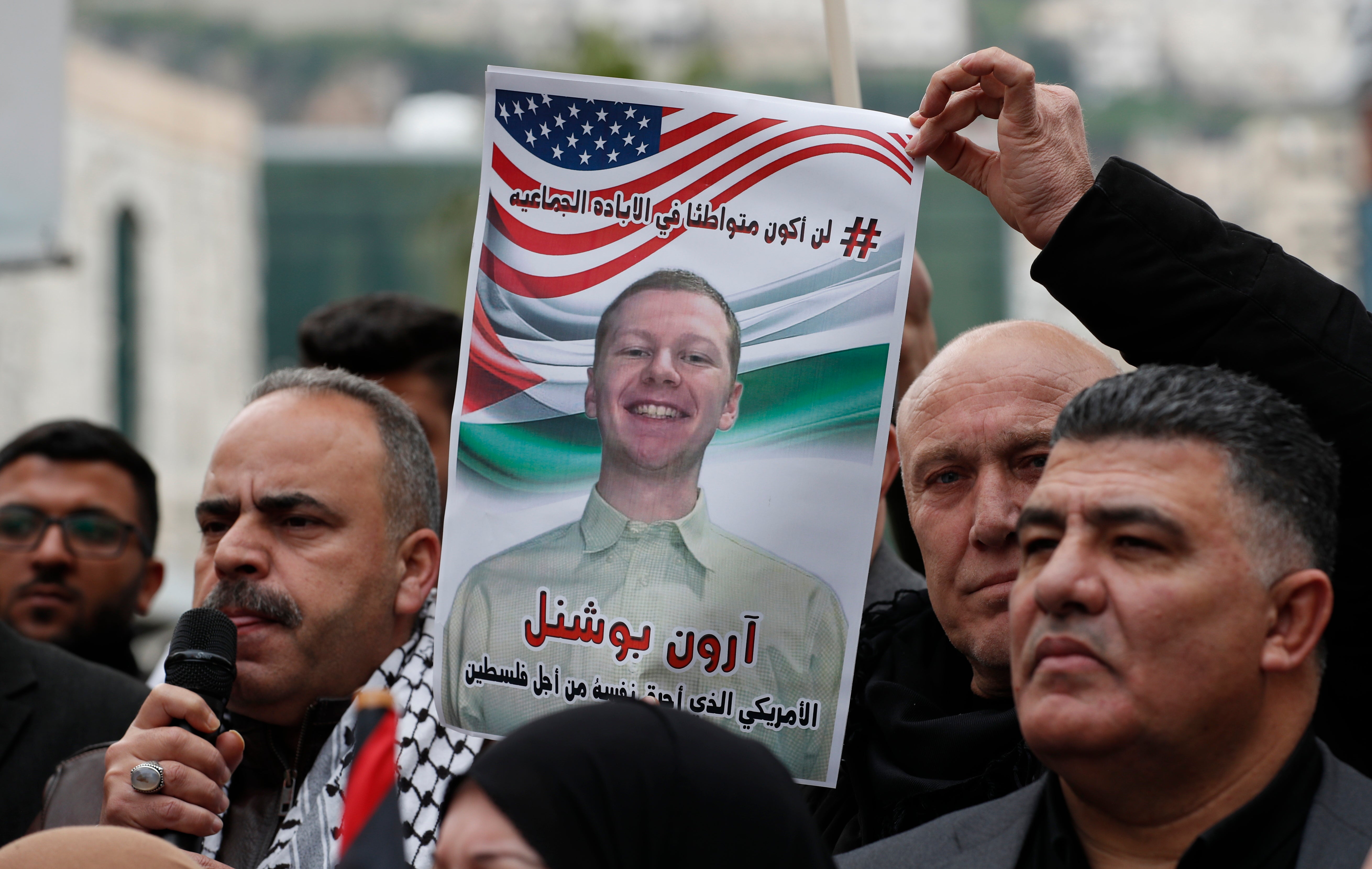 A man holds up a photo of late US airman Aaron Bushnell, who died of his injuries after setting himself on fire outside the Israeli embassy in Washington DC