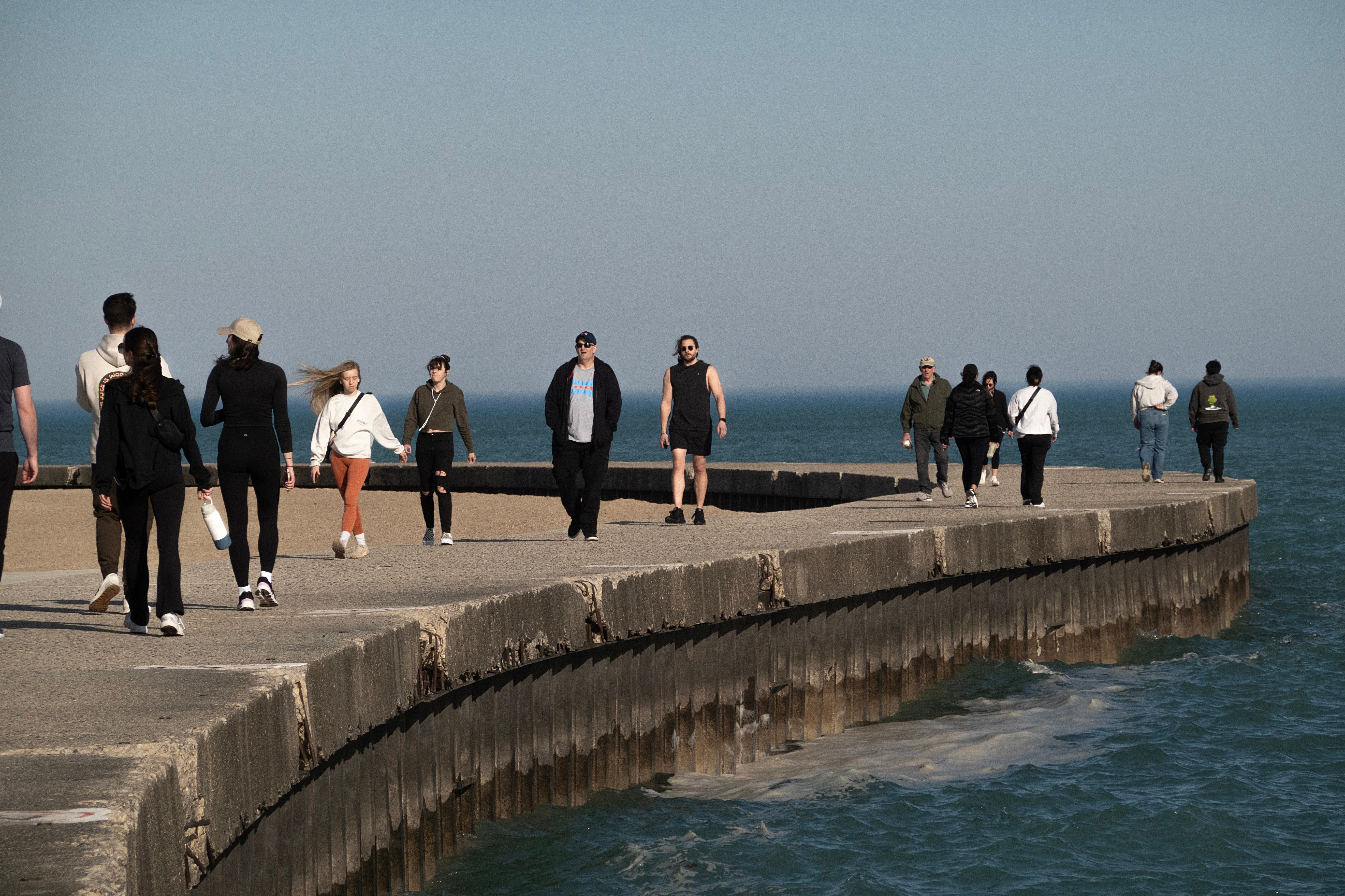 People walk along a boardwalk on a spring-like February day in Chicago