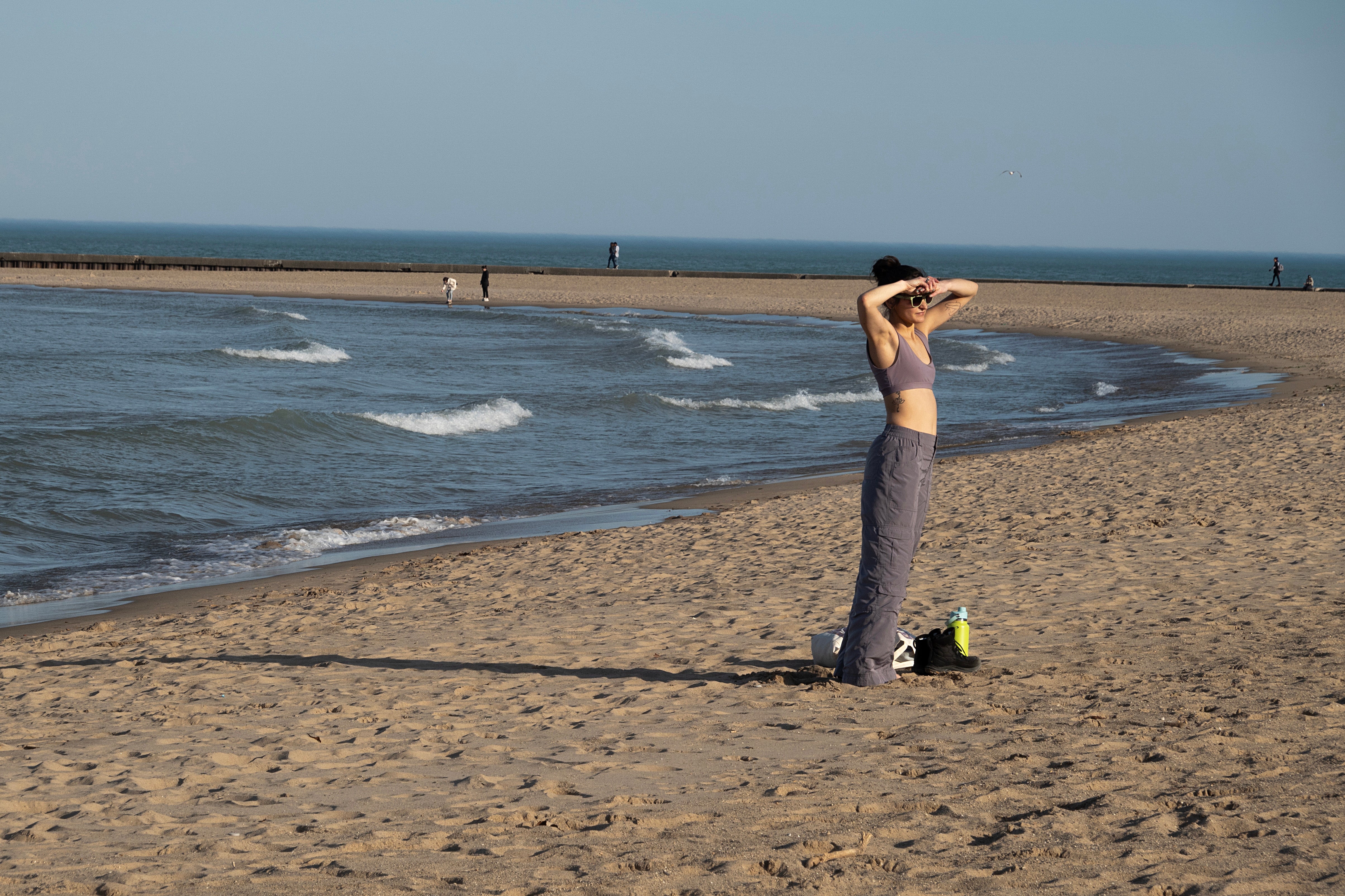 A woman stands on the beach as spring-like temperatures hit Chicago on Monday