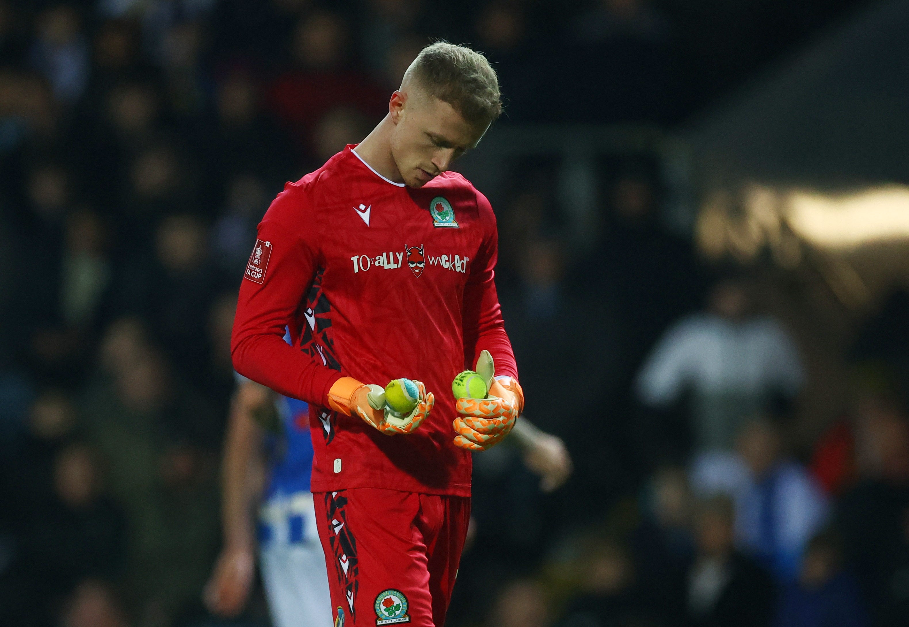 Blackburn Rovers' Aynsley Pears collects tennis balls thrown onto the pitch by fans