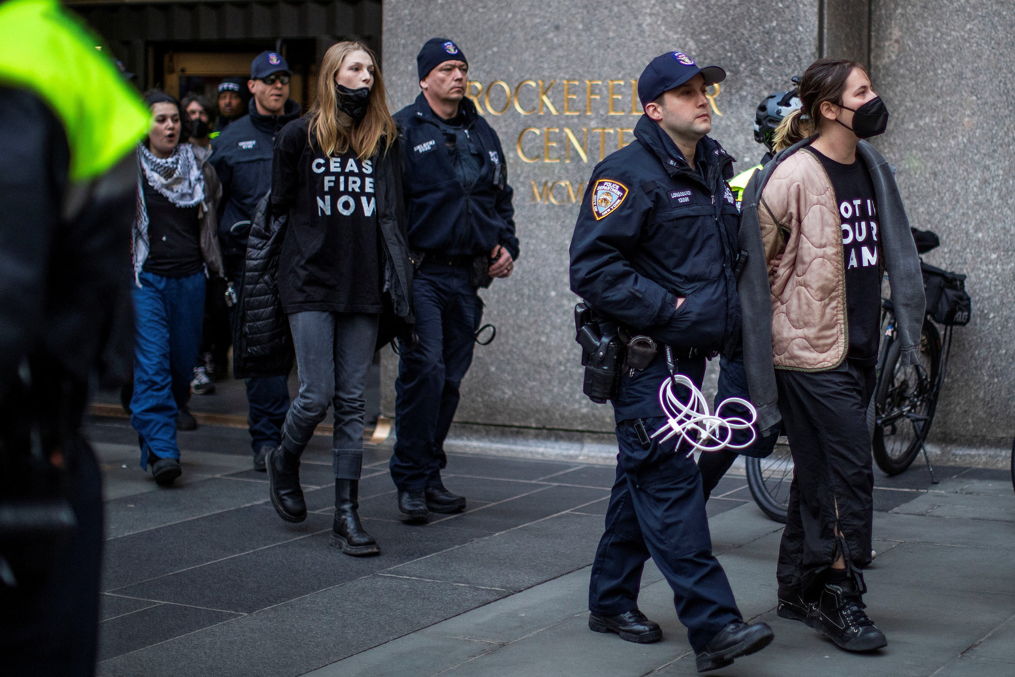 Schafer and protesters being lead out of the Rockefeller Centre