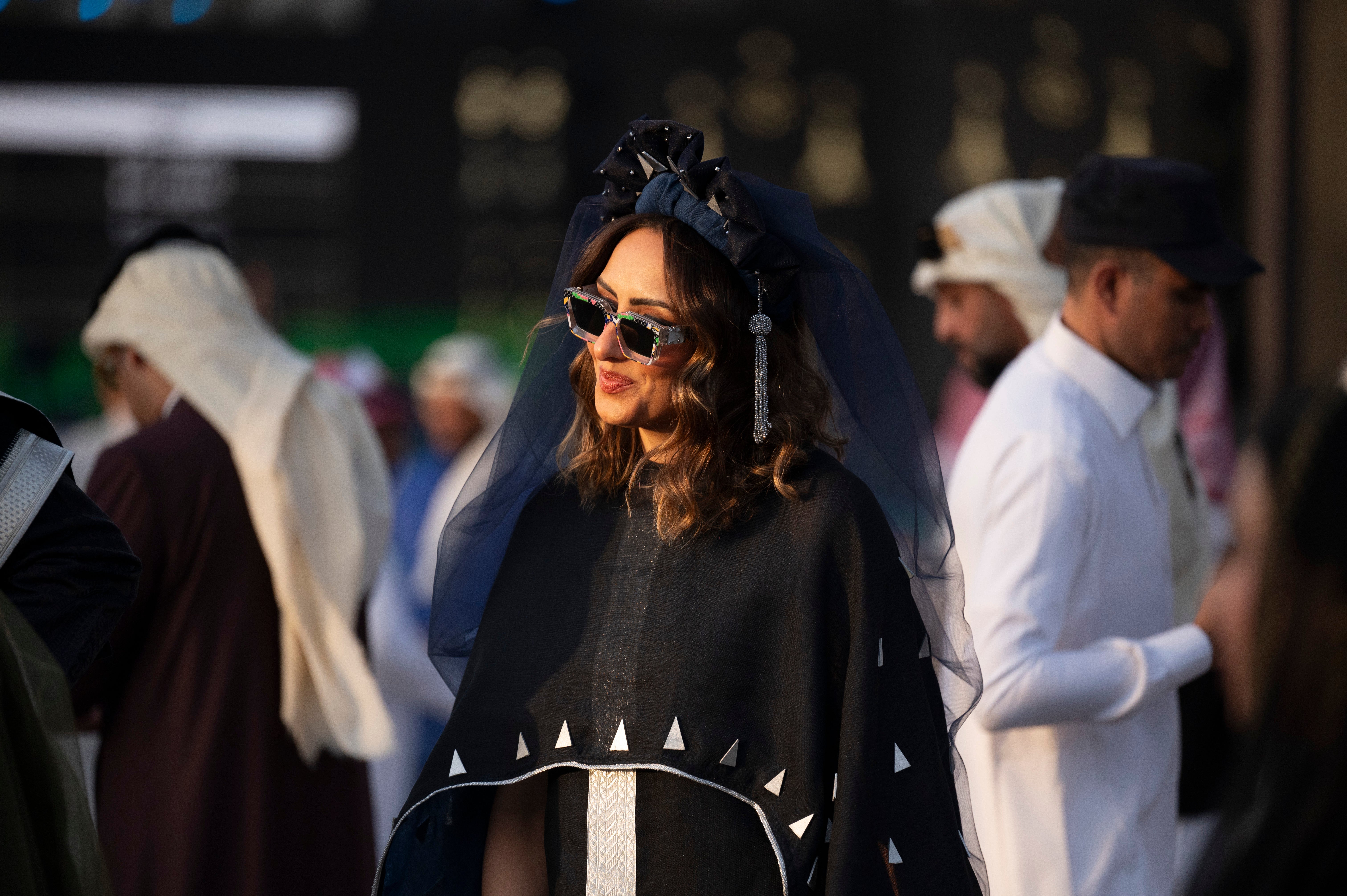 A racegoer blends a European style headdress with a traditional thobe