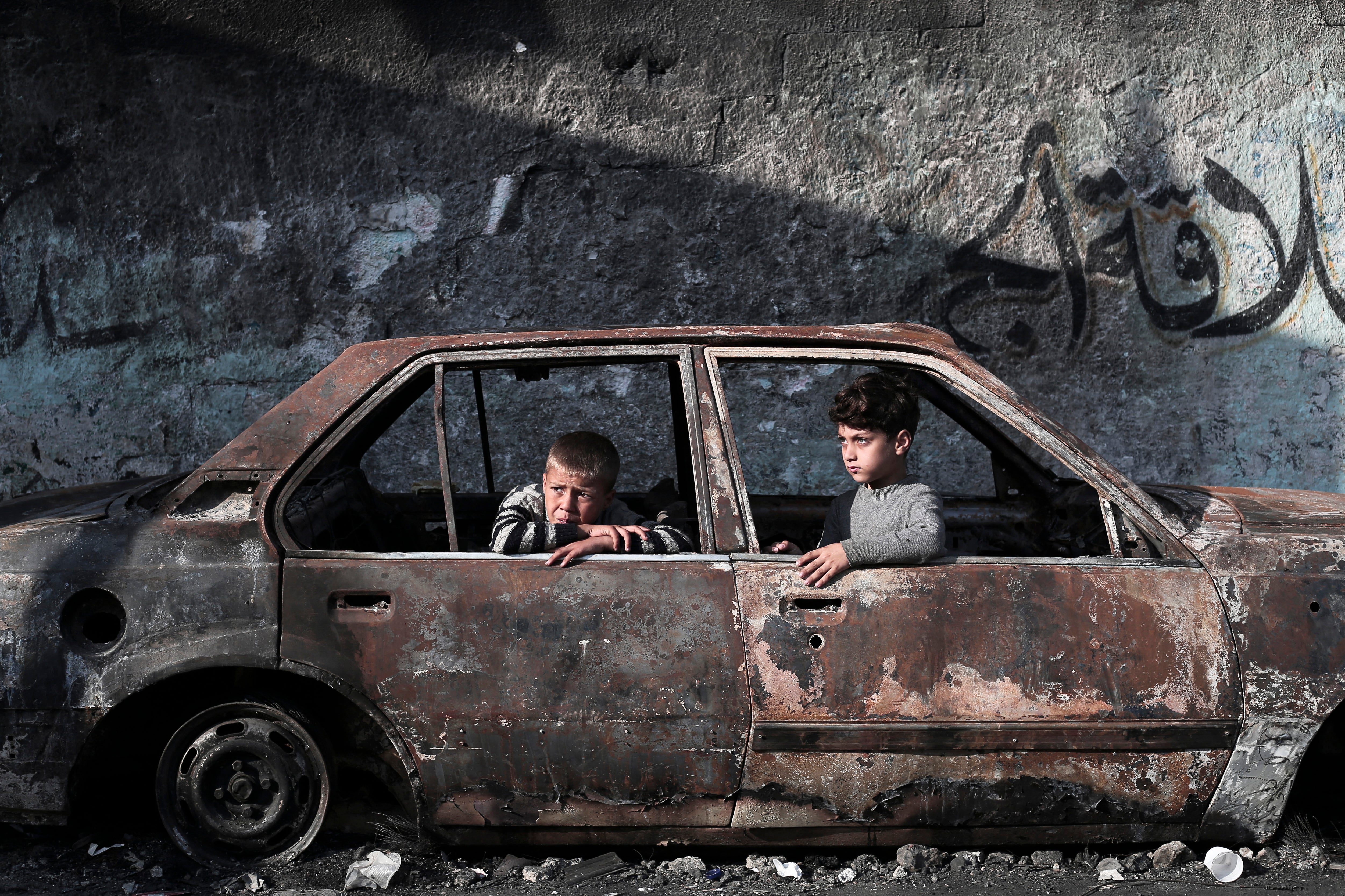 Children sit in a destroyed car in Rafah