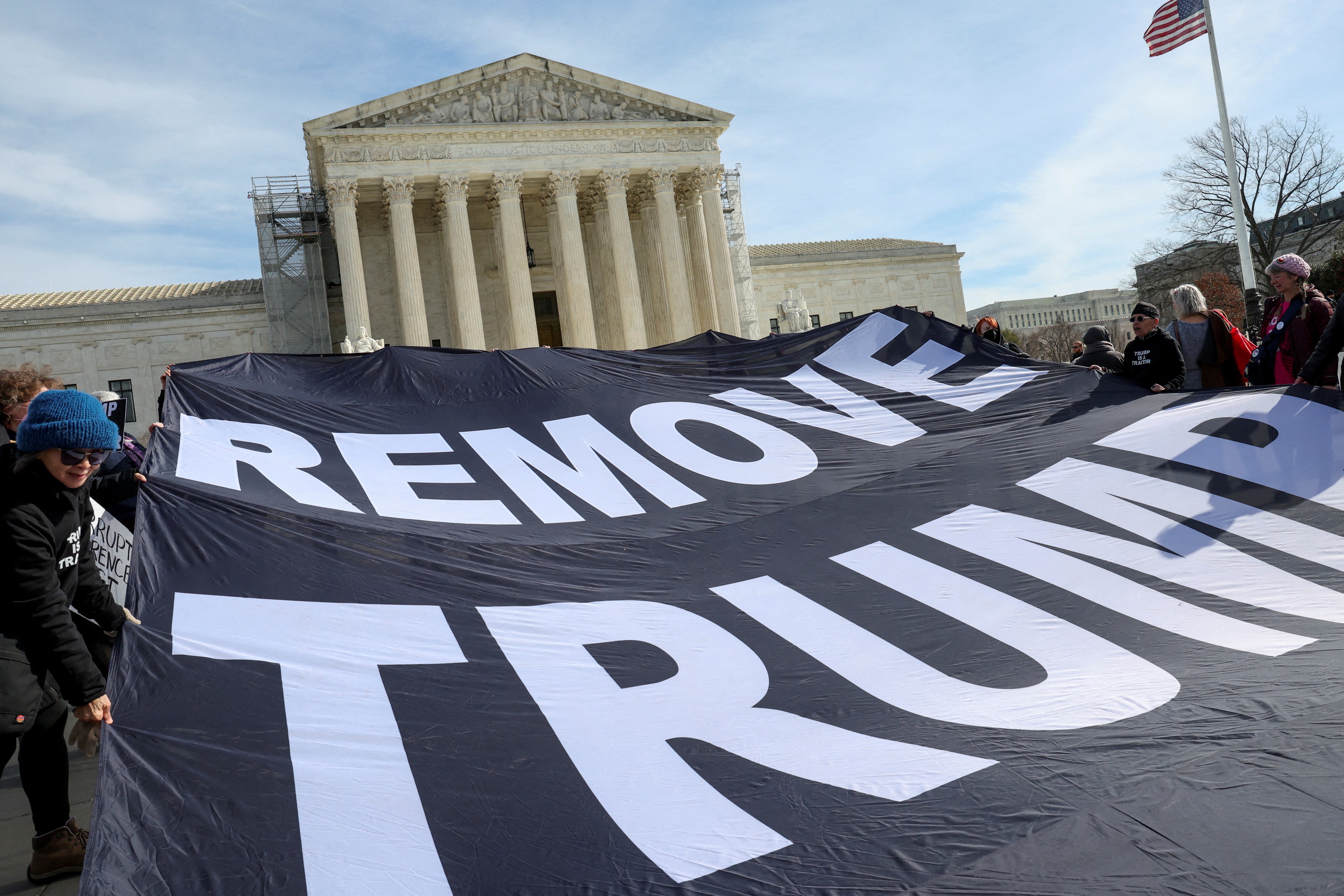 Activists hold up a banner following arguments in Donald Trump’s appeal of his removal from Colorado ballots on 8 February