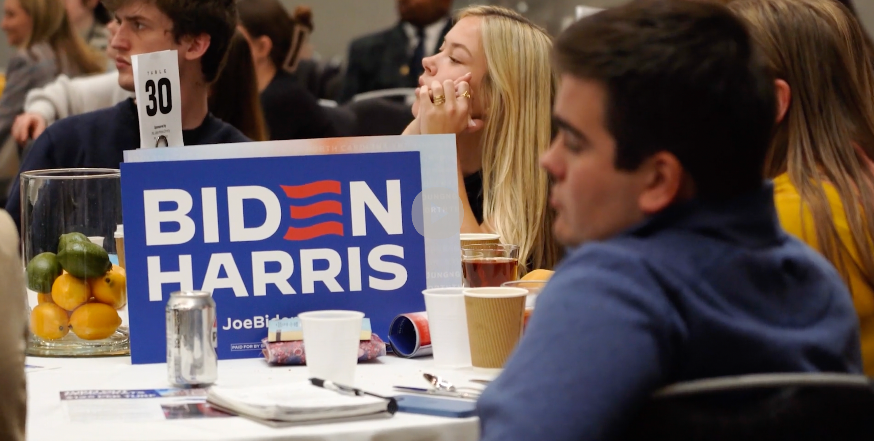 Young Democrats sit around tables and listen to speeches at the Young Democrats of North Carolina Convention