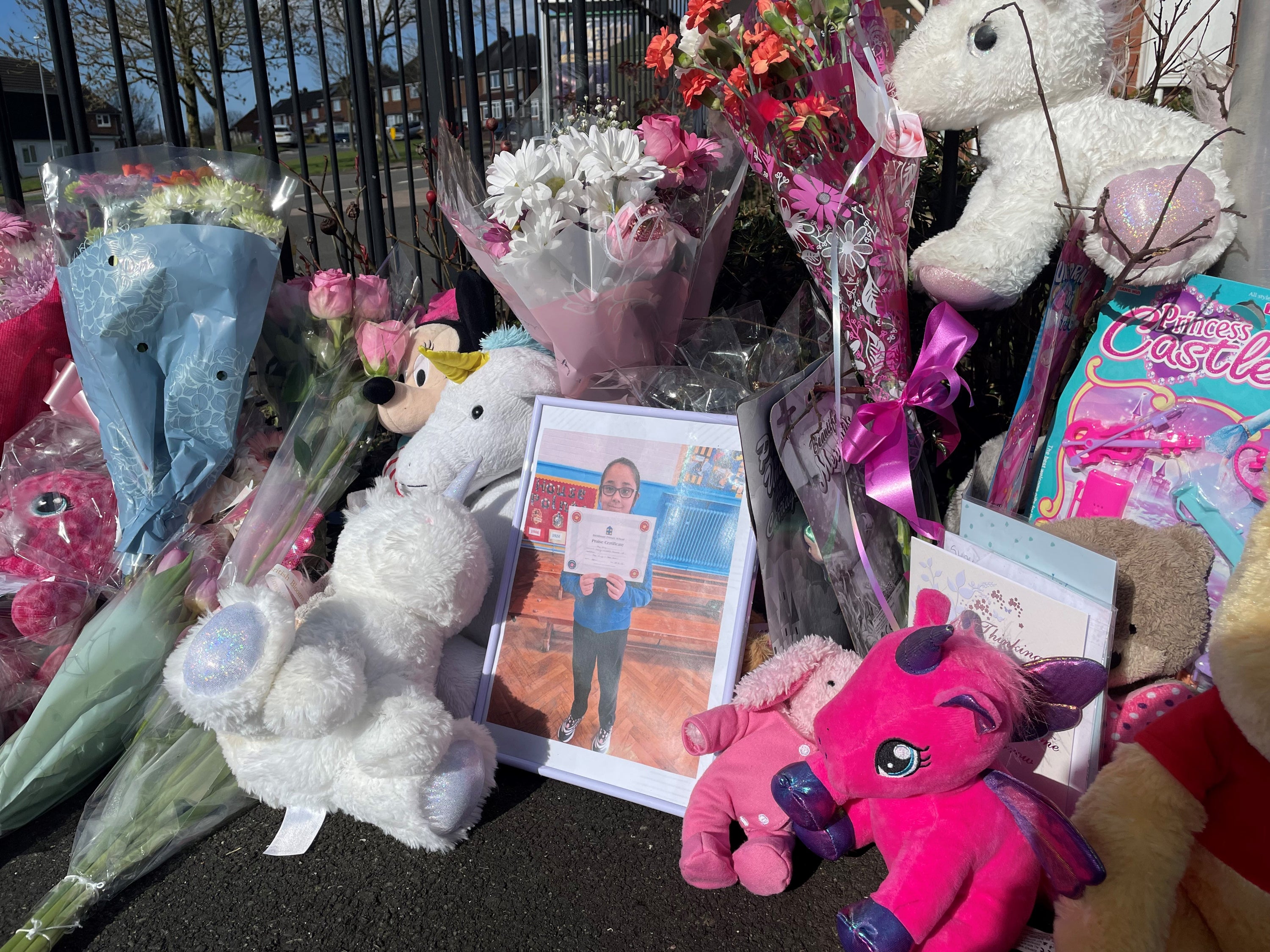 Floral tributes to a 10-year-old girl, named locally as Shay, placed near her home alongside a picture of her holding a Brickhouse Primary School praise certificate