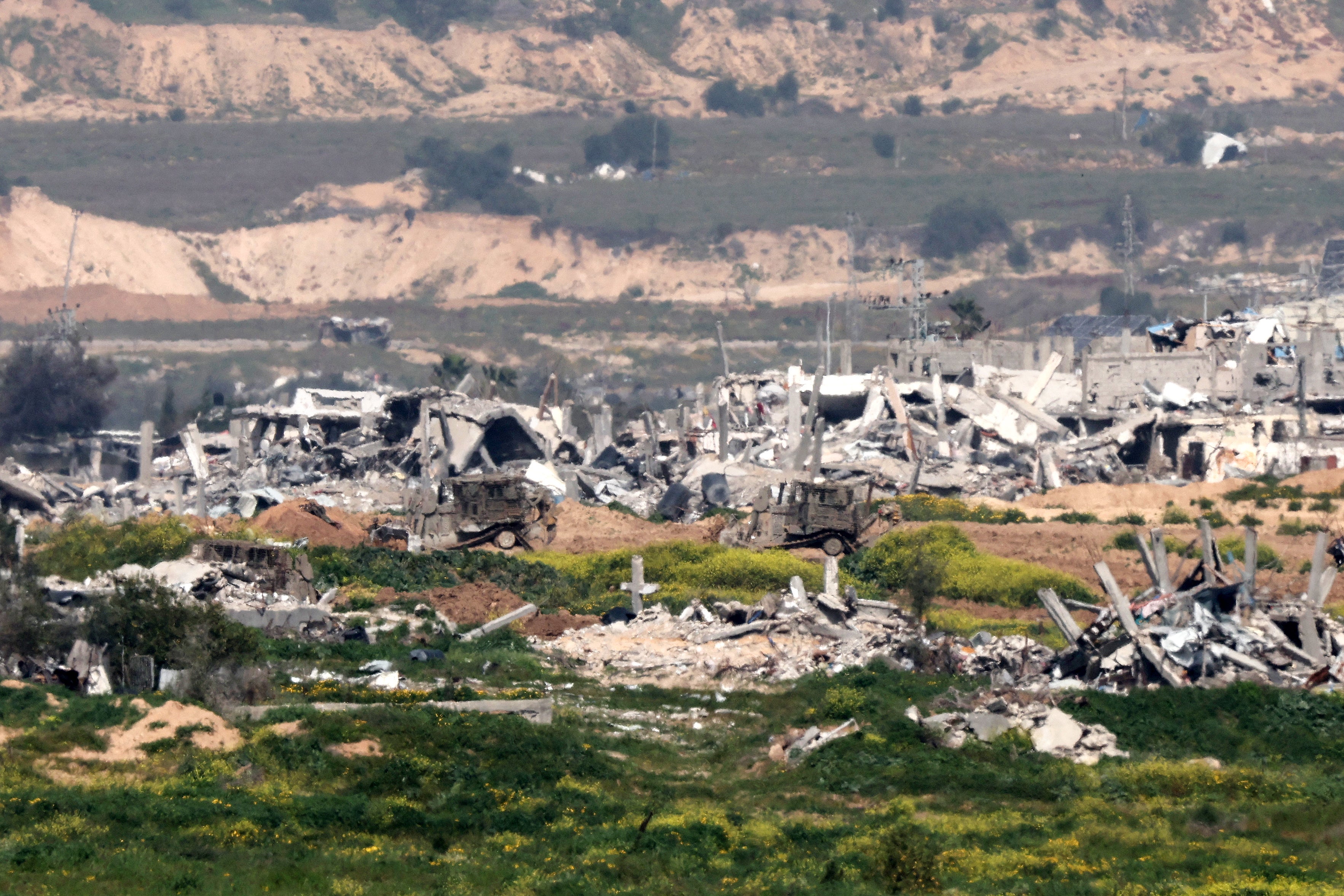 This picture taken from Israel near the border with the Gaza Strip shows Israeli army vehicles moving inside Gaza on 6 March 2024