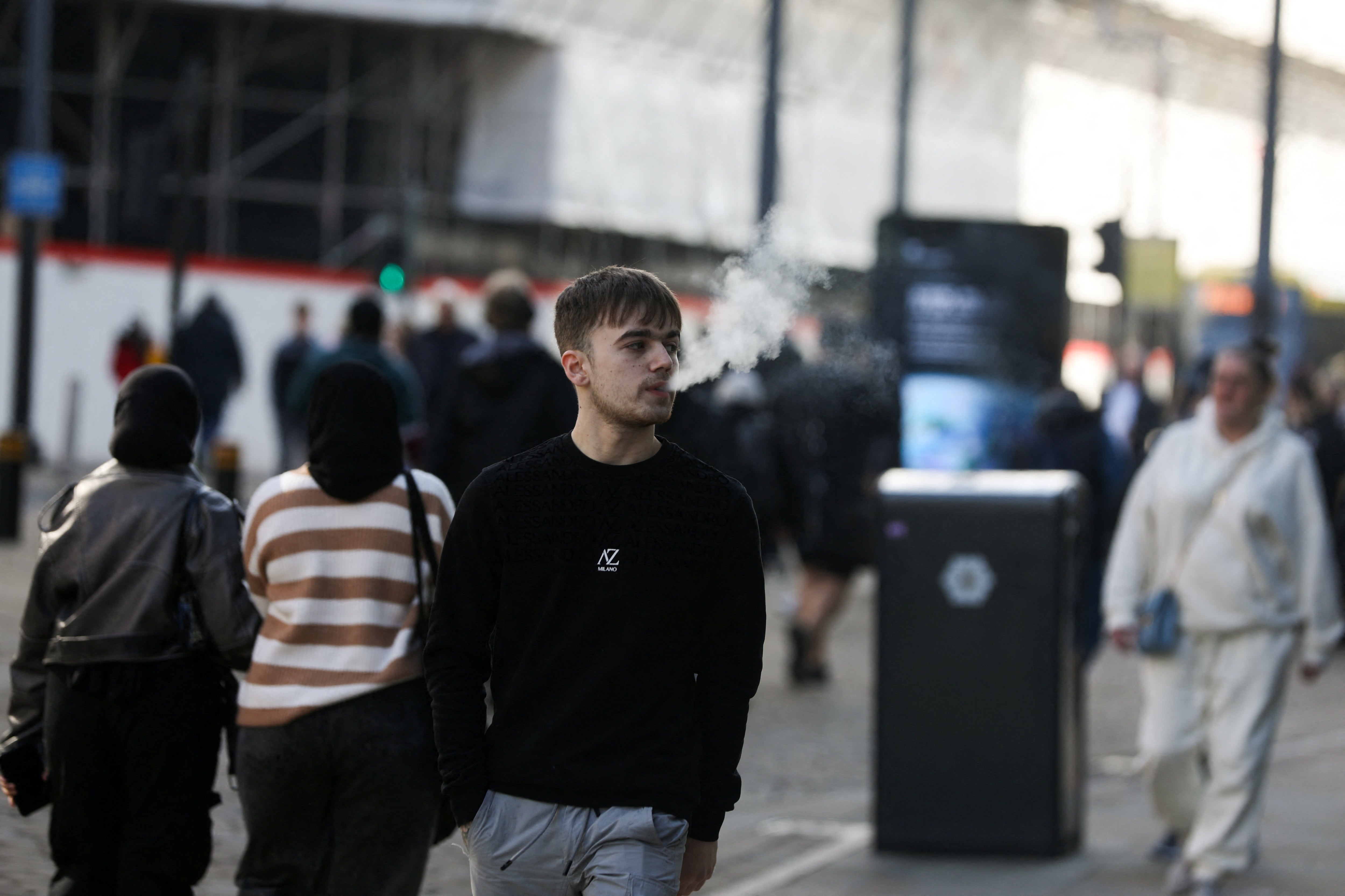 A man vapes on a street in Manchester