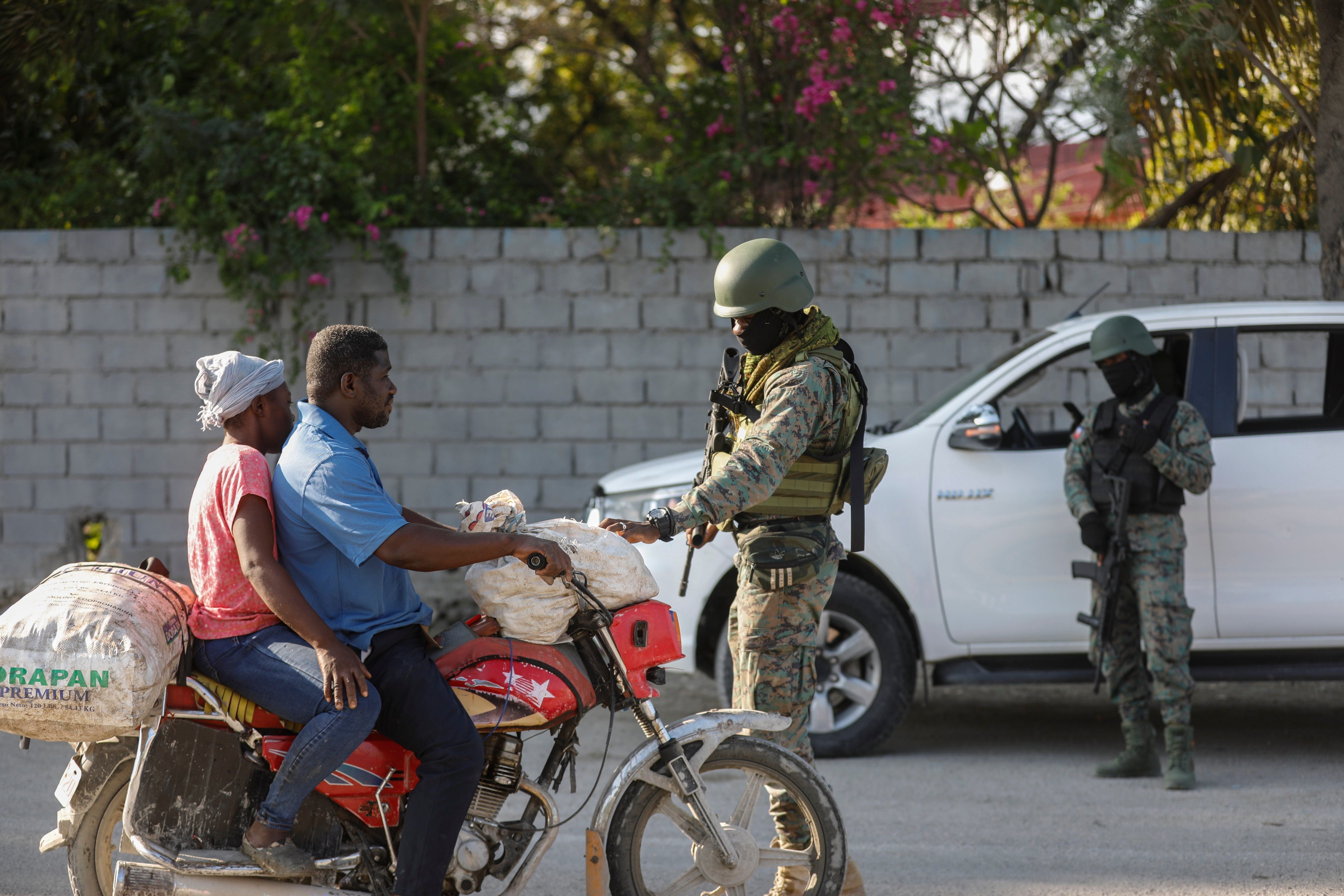 Soldiers inspect commuters at the entrance of the international airport in Port-au-Prince, Haiti, Wednesday, March 6