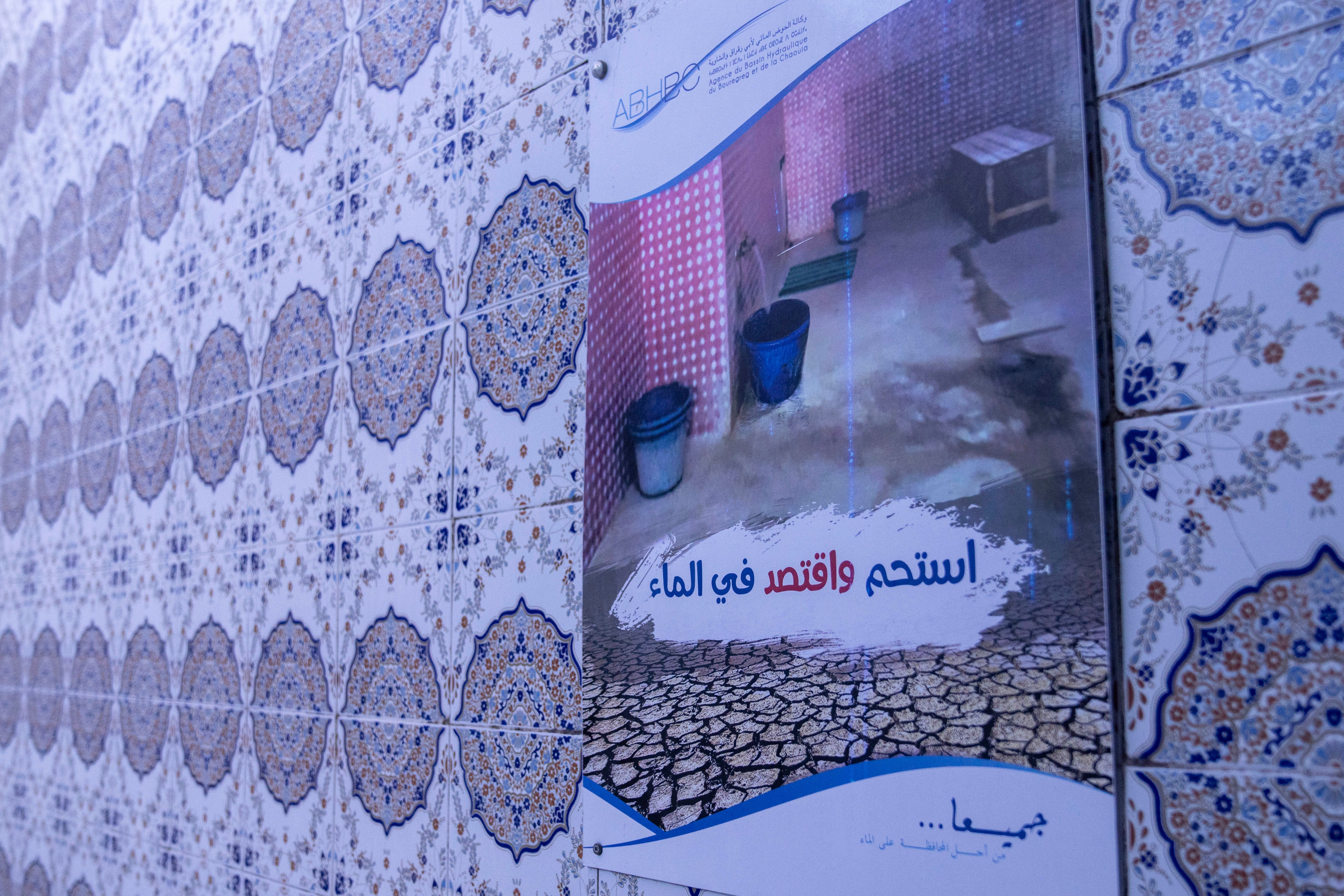 A notice poster encourages people to preserve water inside a Moroccan traditional bath, known as hammam