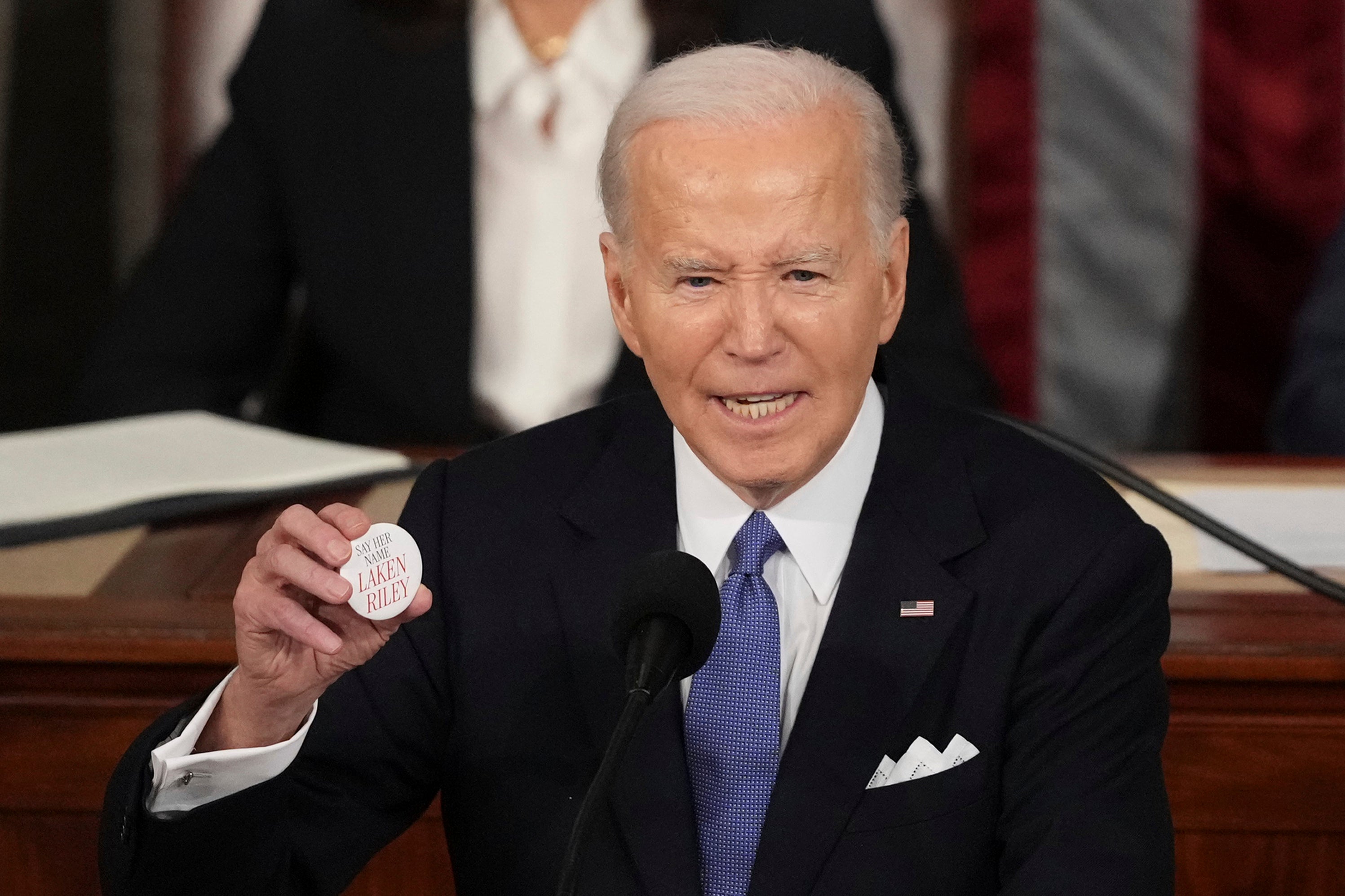 President Joe Biden holds up a Laken Riley button as he delivers the State of the Union address