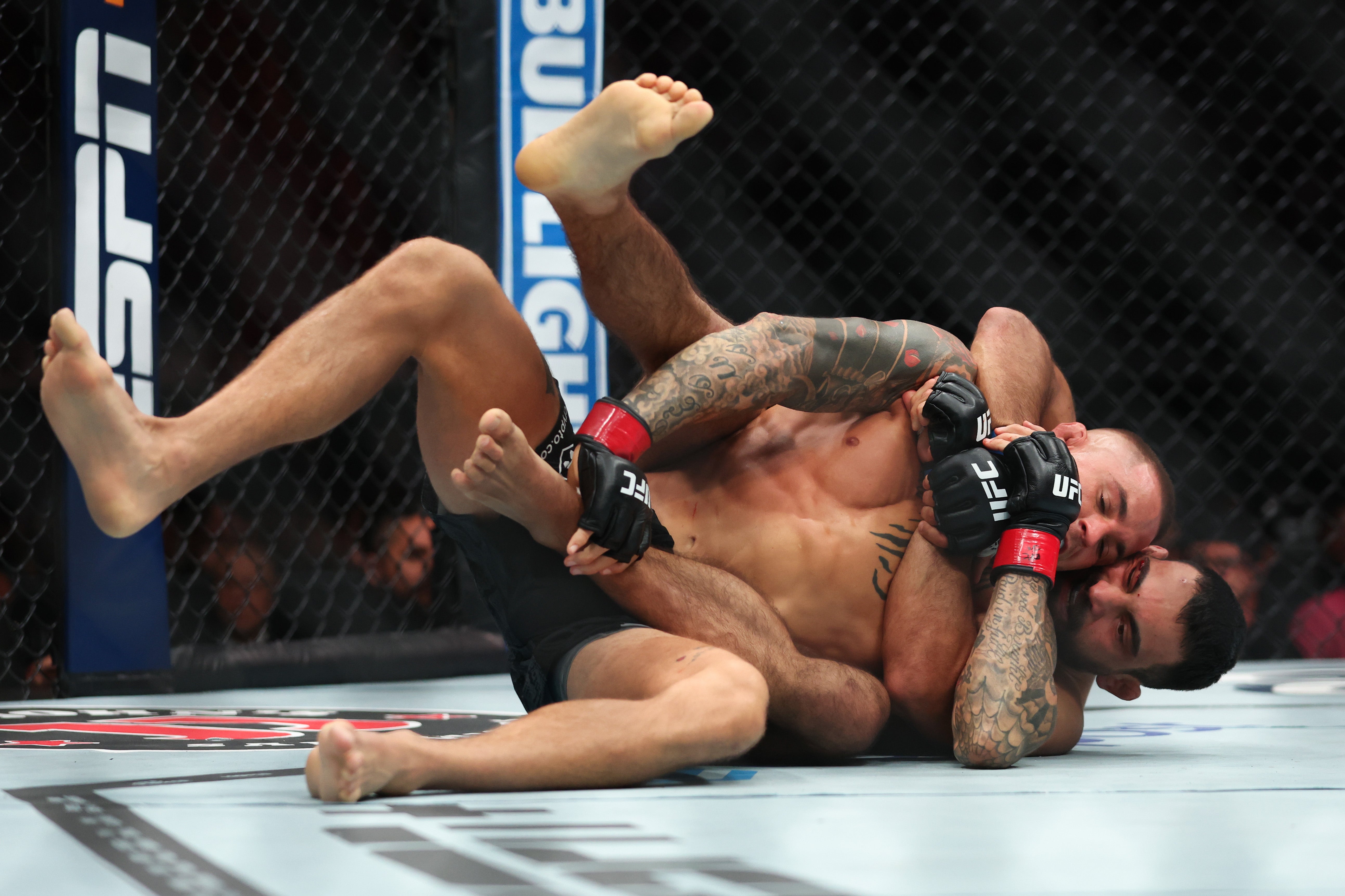 Saint-Denis (right) goes for a rear naked choke against Poirier