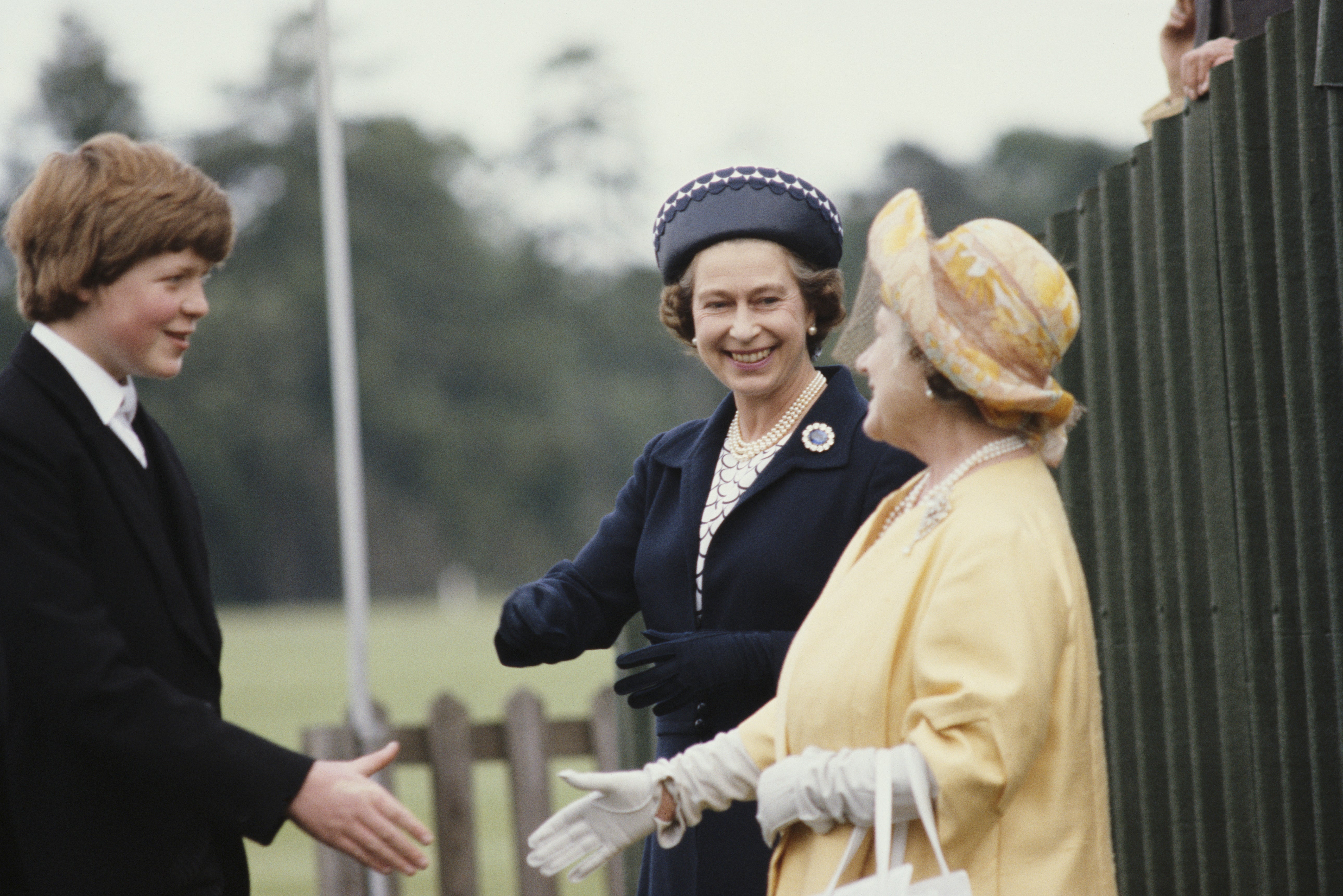 Queen Elizabeth II and the Queen Mother shake hands with a young Charles Spencer in 1978