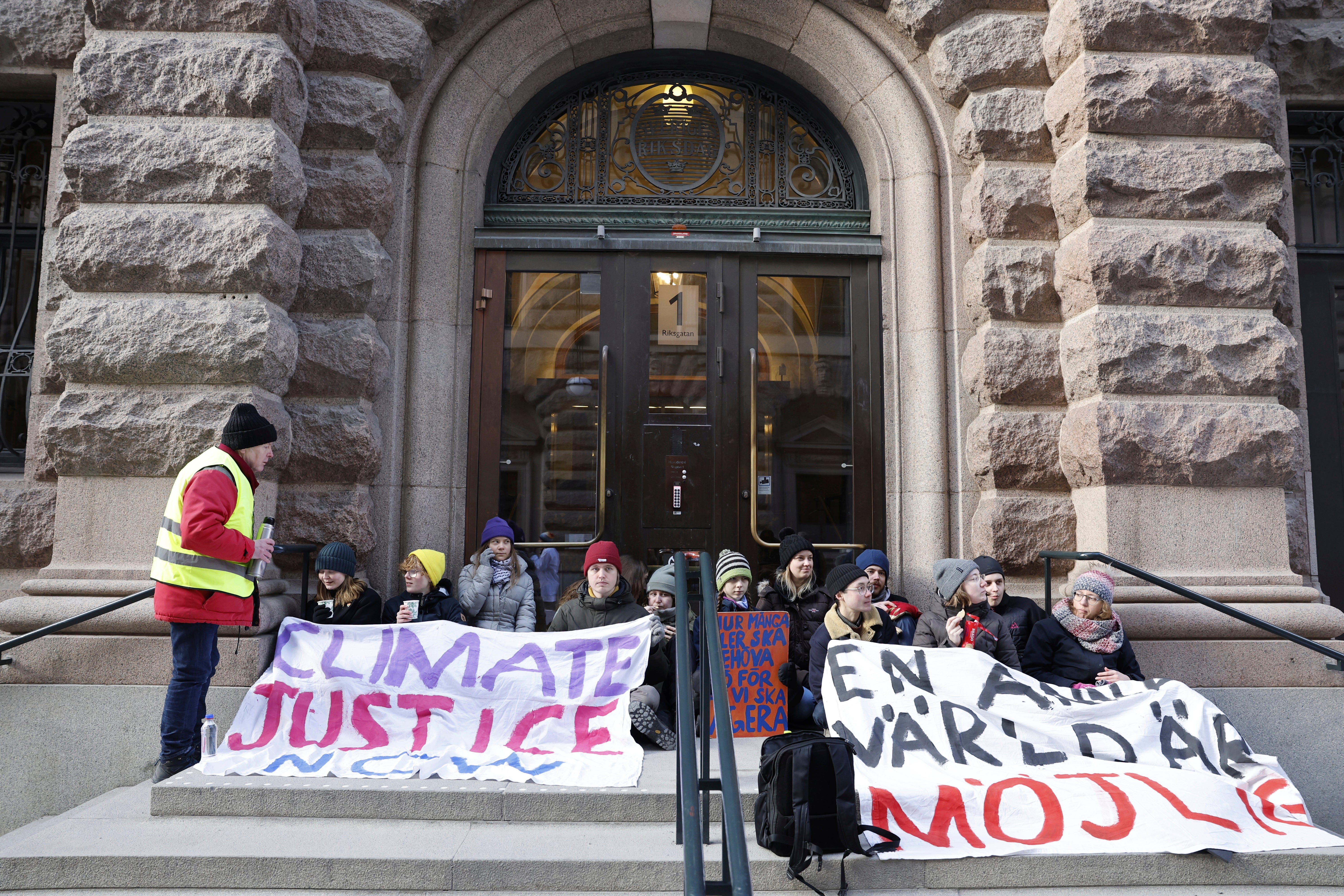 Greta Thunberg, third from left, and other protesters block the entrance of the Swedish parliament during a climate protest in Stockholm, Sweden, on Monday