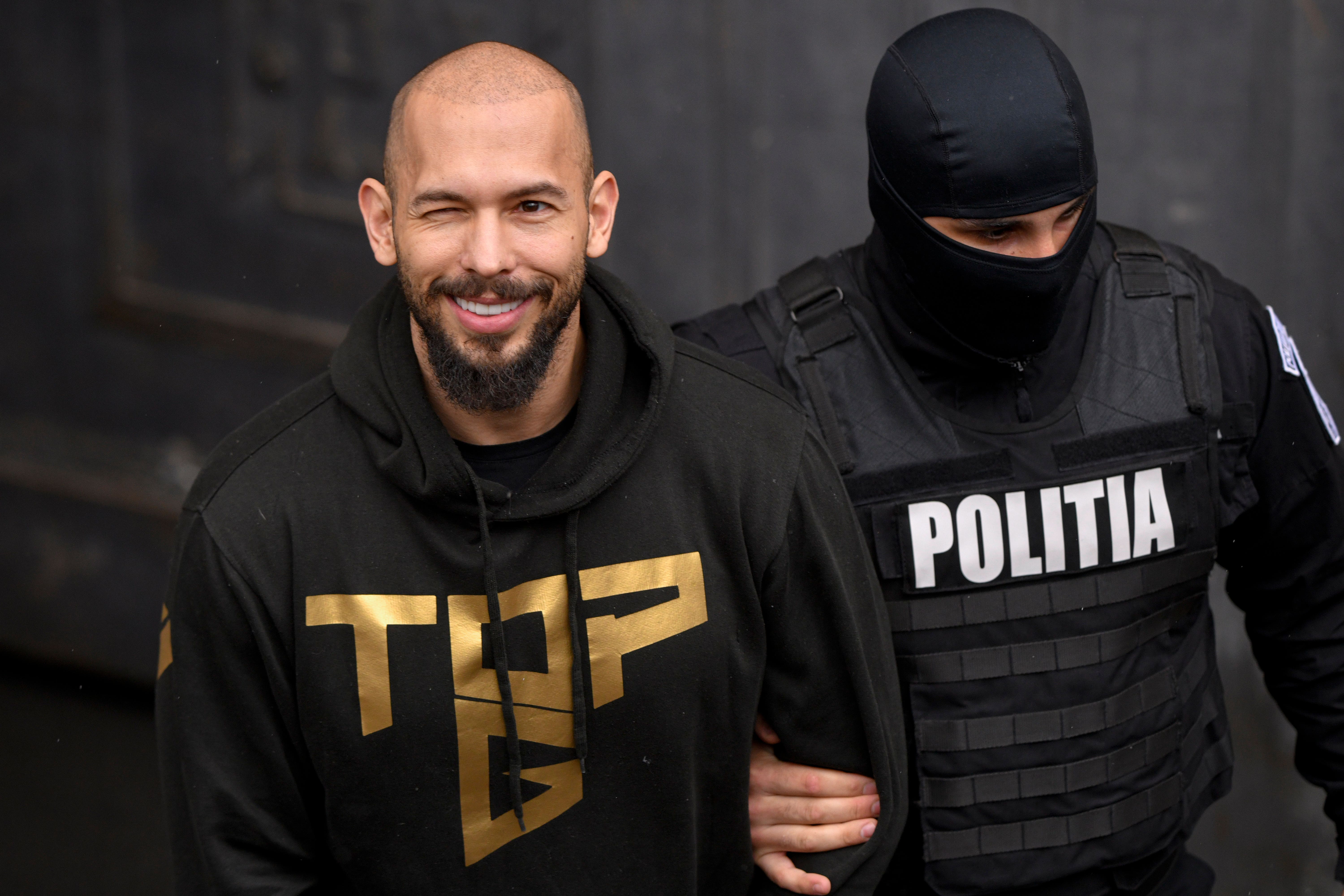 A police officer escorts Andrew Tate from the appeal court in Bucharest, Romania