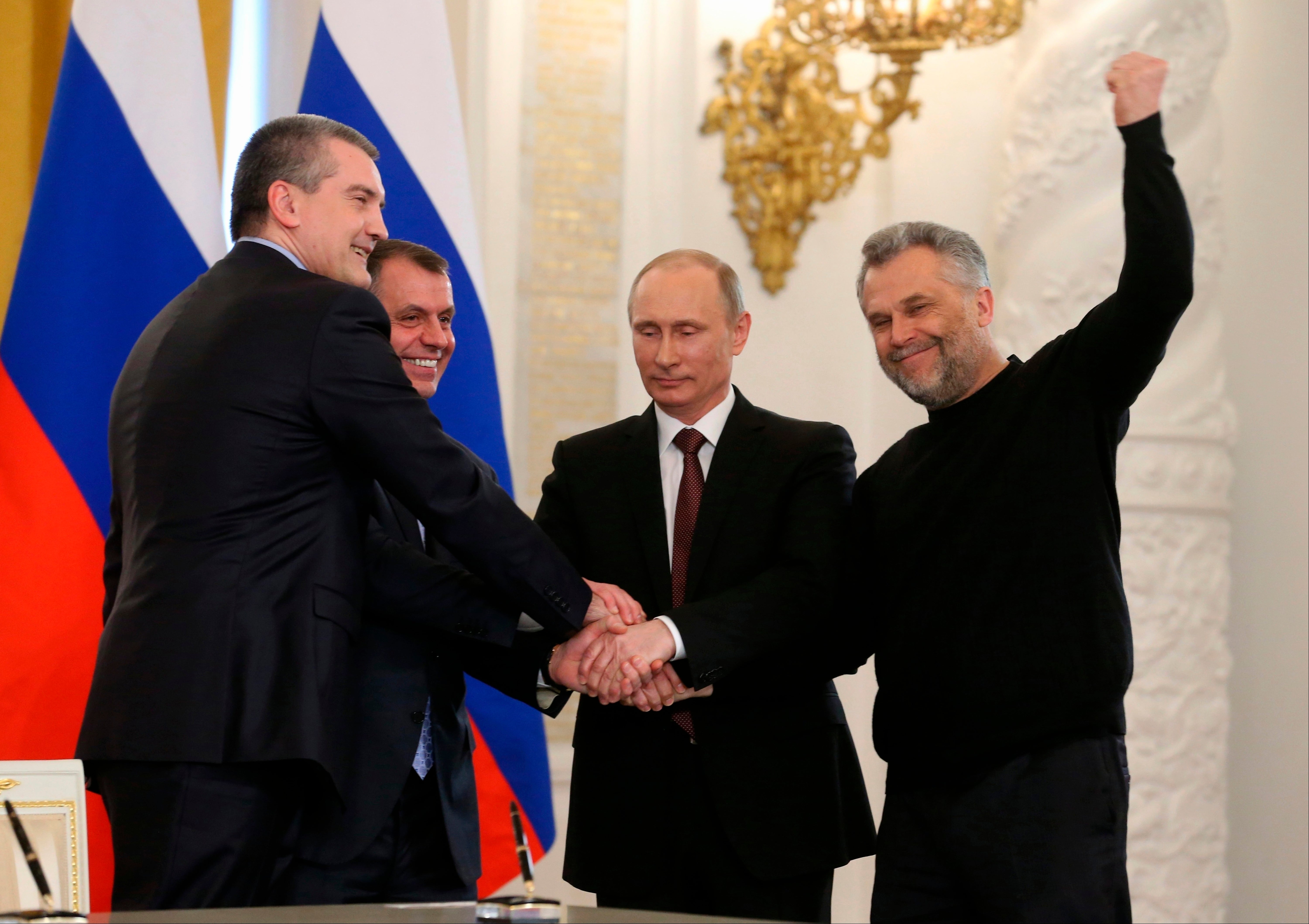 FILE - Russian President Vladimir Putin, second right, Speaker of the Crimean legislature Vladimir Konstantinov, second left, Crimean Premier Sergei Aksyonov, left, and Sevastopol Mayor Alexei Chalyi, right, shake hands after signing a treaty for Crimea to join Russia