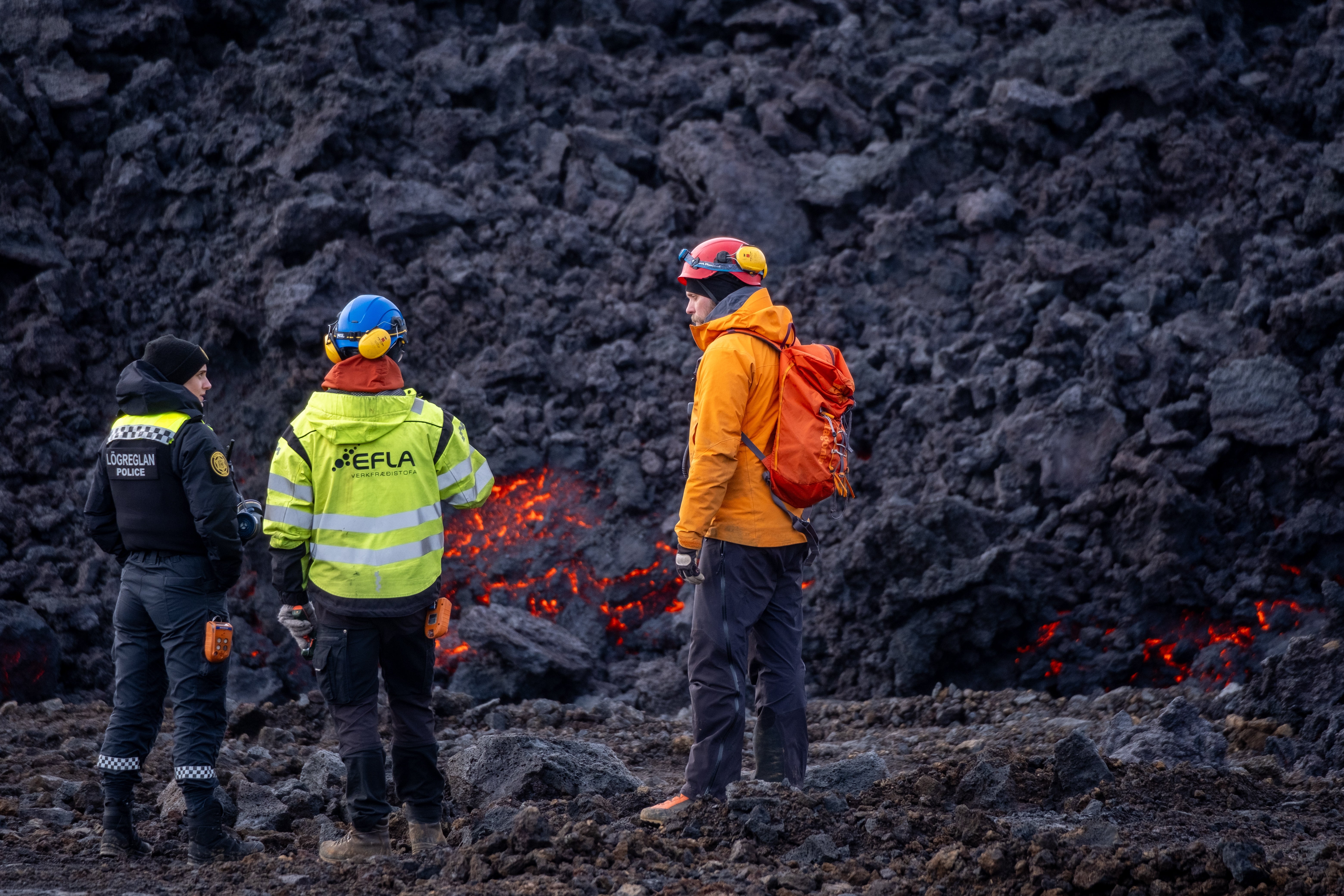 A police officer and engineer stand next to the lava field of a volcanic eruption in Iceland