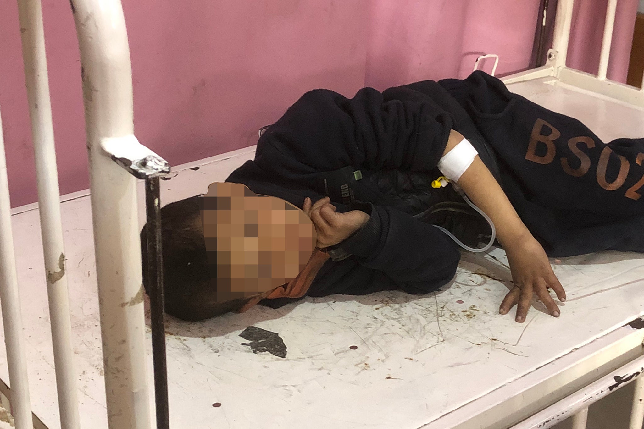 A child requiring an IV drip rests on a bed inside the hospital