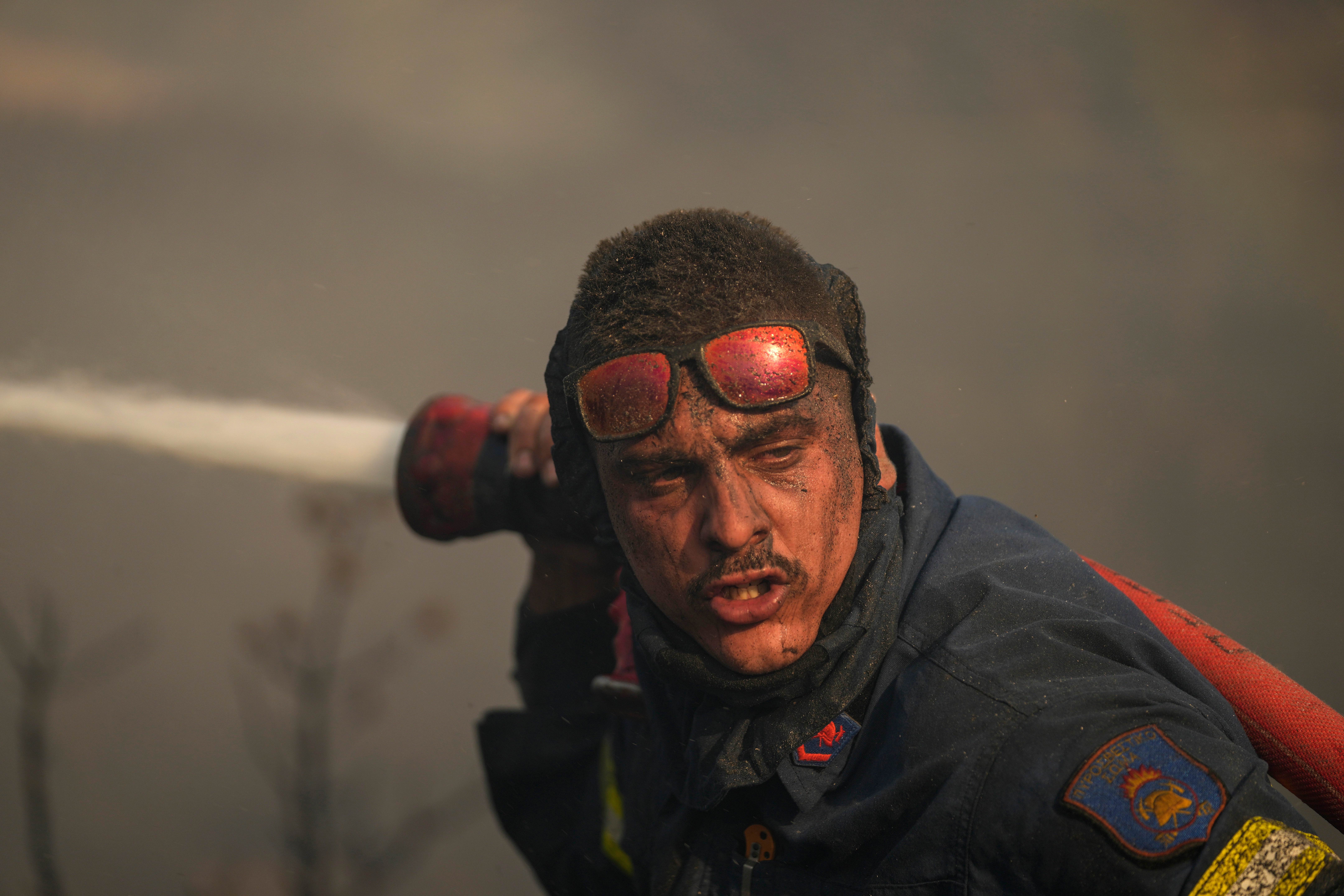 A firefighter sprays water at a fire on the mount of Penteli, in northern Athens, Greece on July 19, 2022