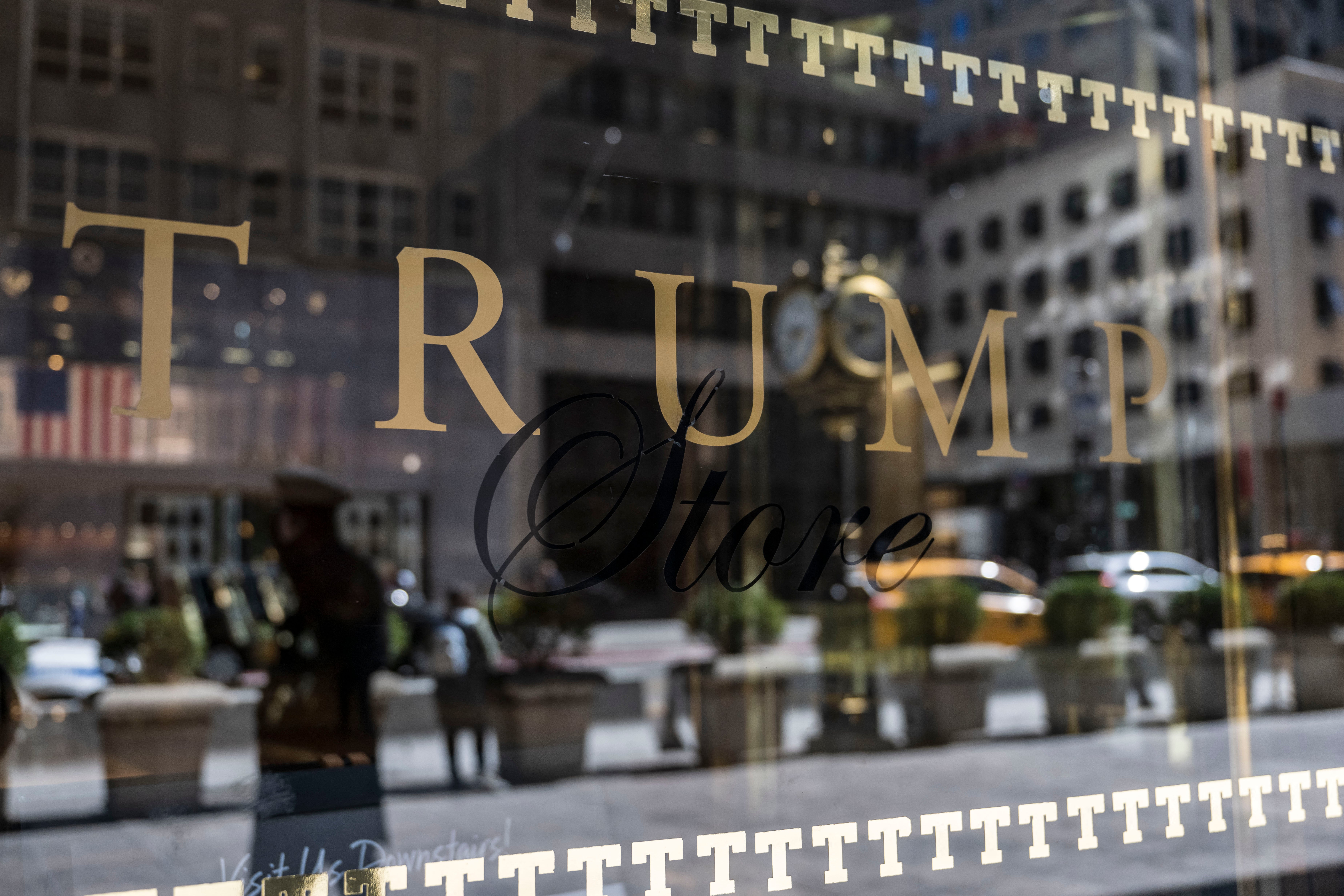 A security guard reflected in the glass as he patrols outside Trump Tower