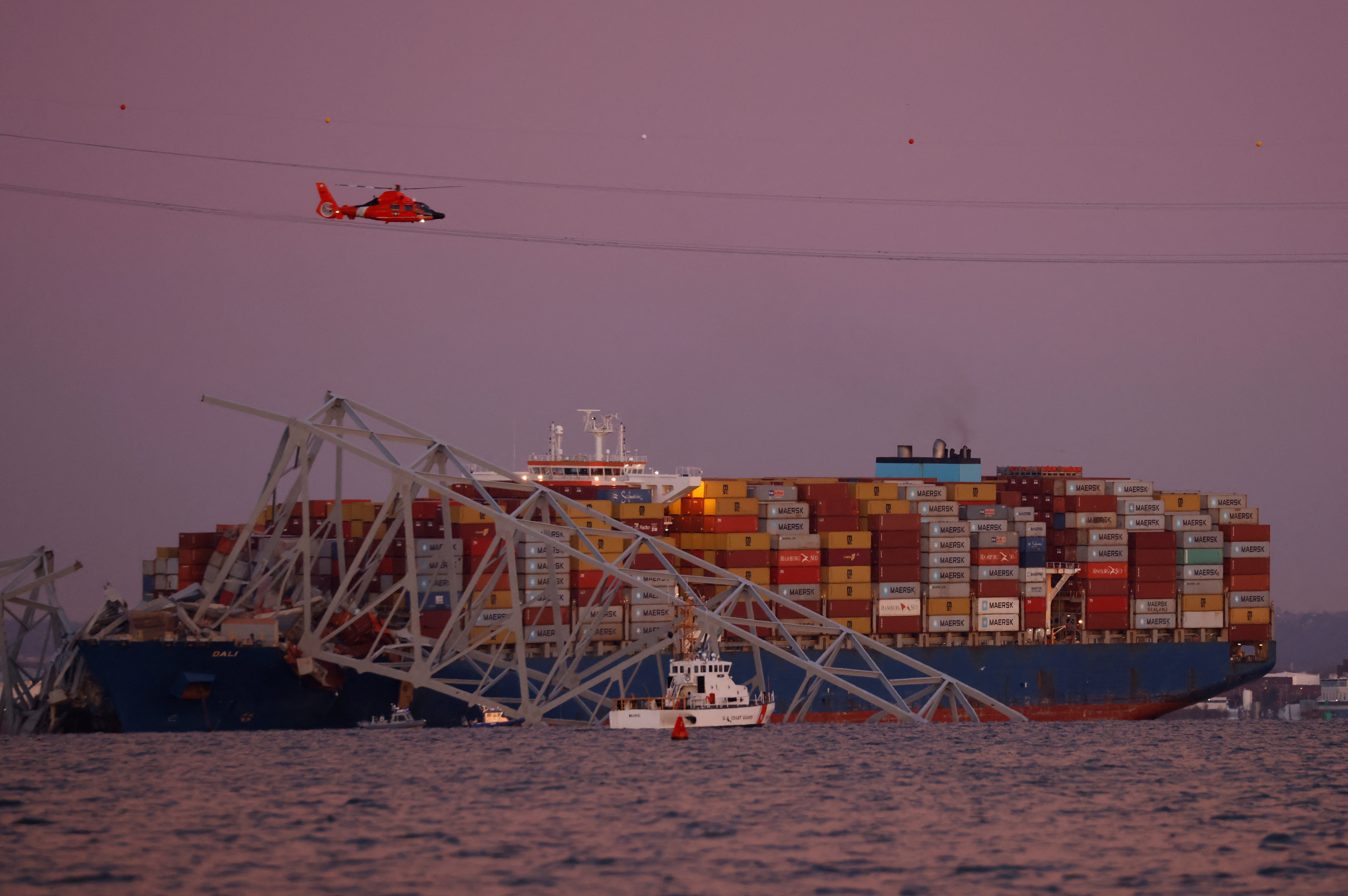 A helicopter flies over the scene of the Francis Scott Key Bridge collapse in Baltimore, Maryland