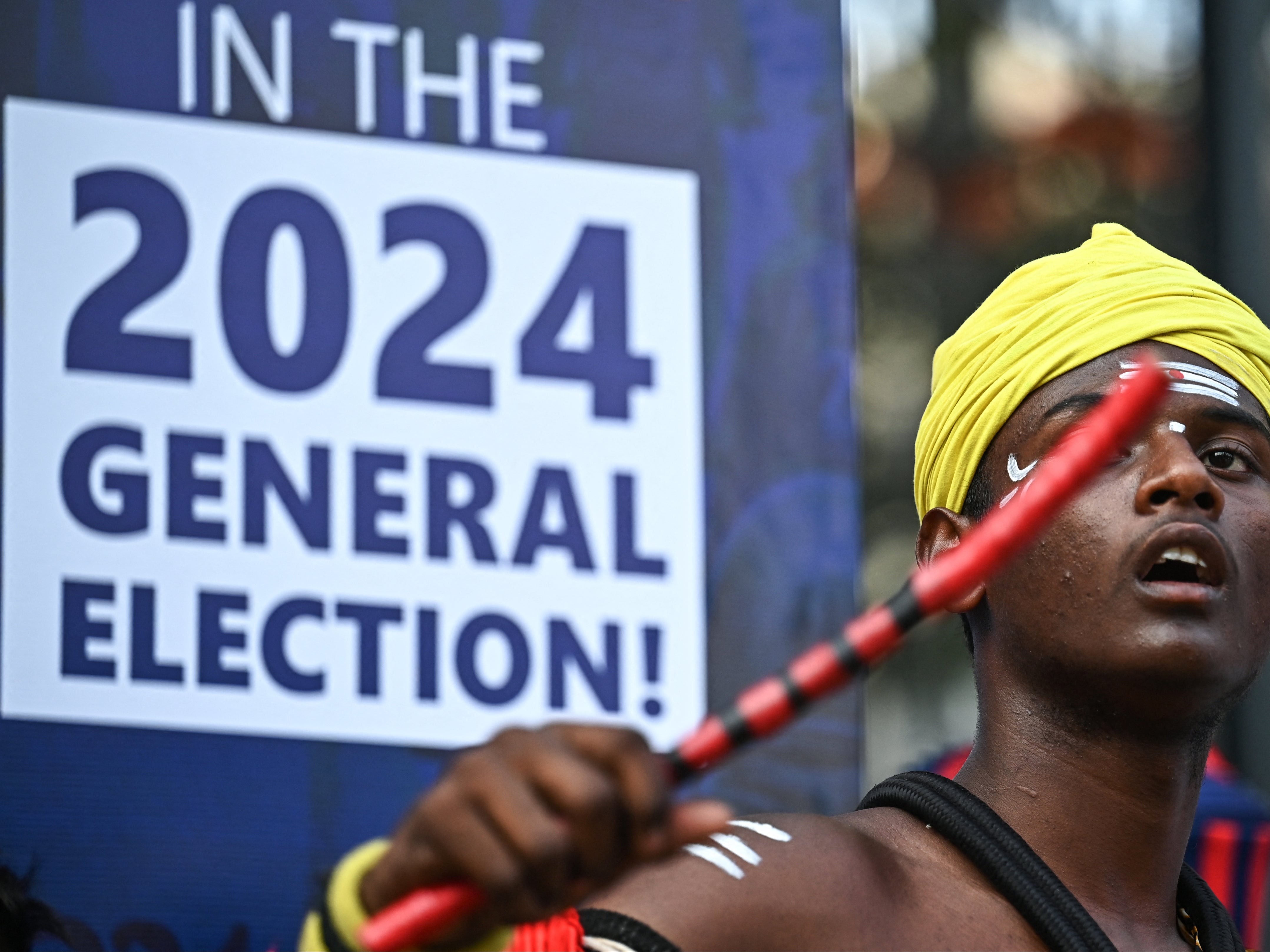 An artist dressed in a traditional attire performs in front of an election sign board during the Vote-A-Thon, an awareness campaign organized by the Karnataka’s Chief Electoral Office to encourage 100 percent voting turnout for the upcoming 2024 general elections, in Bengaluru on 17 March 2024