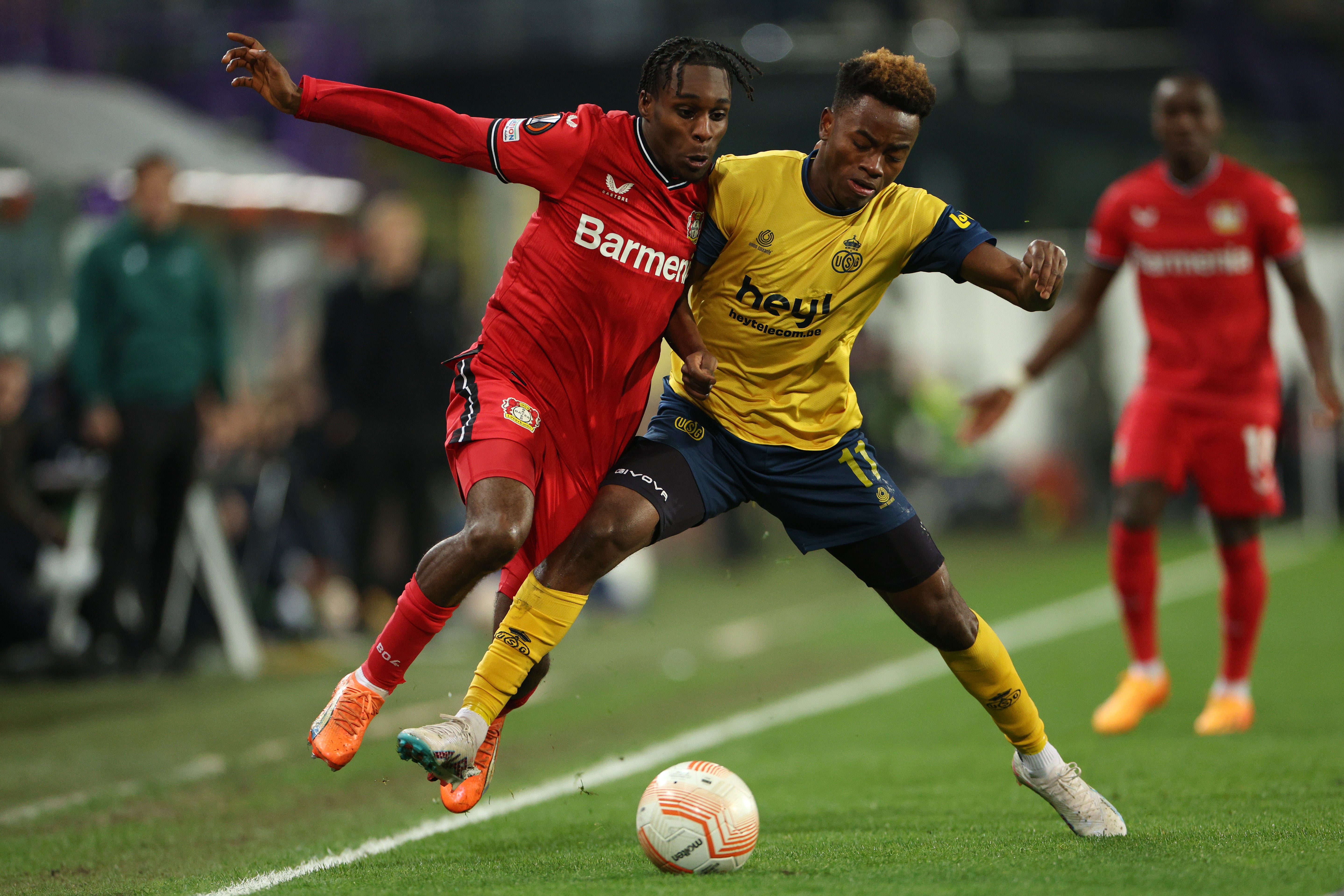 Jeremie Frimpong of Bayer 04 Leverkusen is put under pressure by Simon Adingra of Royale Union Saint-Gilloise