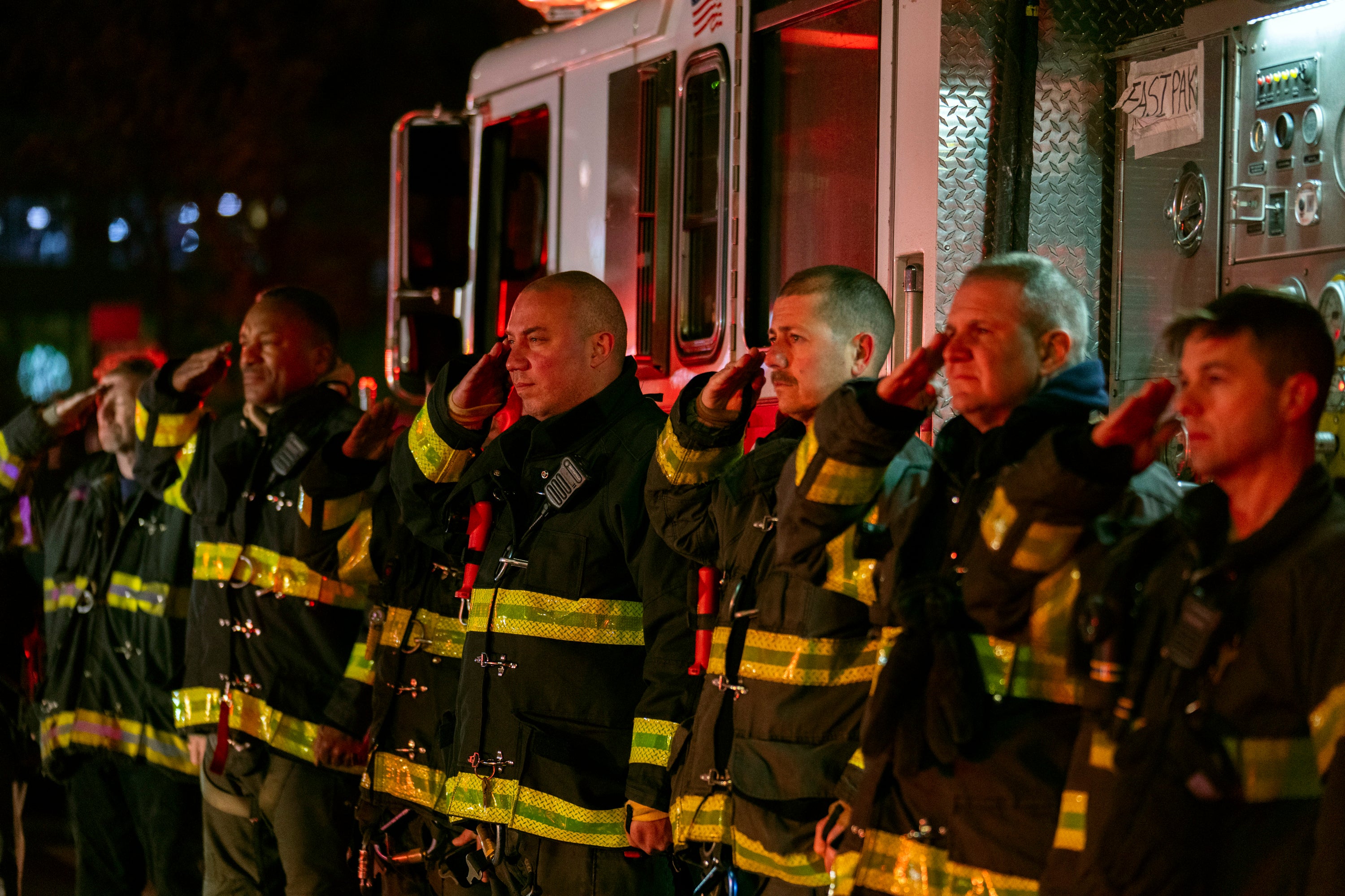 Firefighters salute as the ambulance transporting the body of New York City Police Officer Jonathan Diller exits Jamaica Hospital Medical Center in the Queens